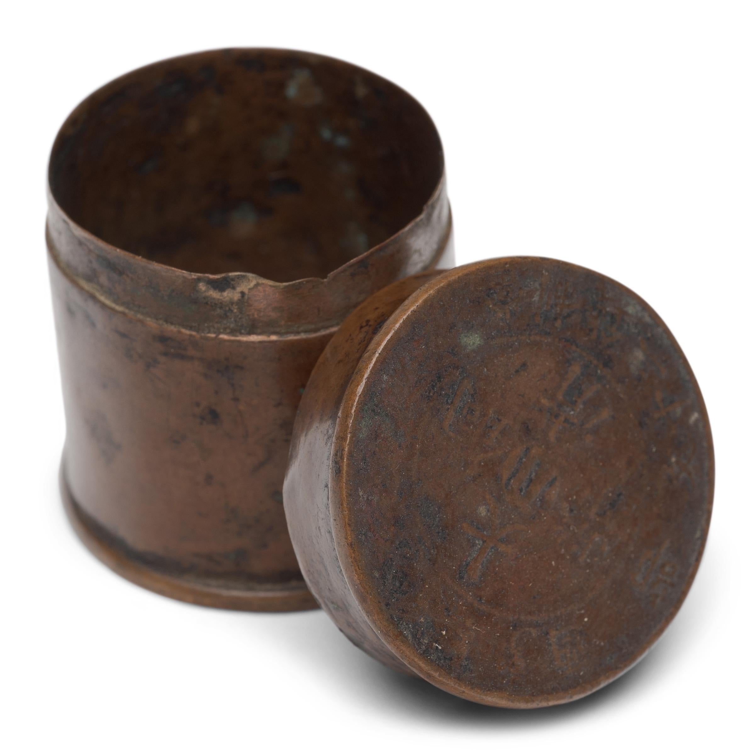 A petite 19th century canister once used to store a smoker's personal supply of opium paste. A keepsake from a bygone era, the small box is formed of antique coins and copper and provided an airtight seal to keep one's opium sticky and malleable.
