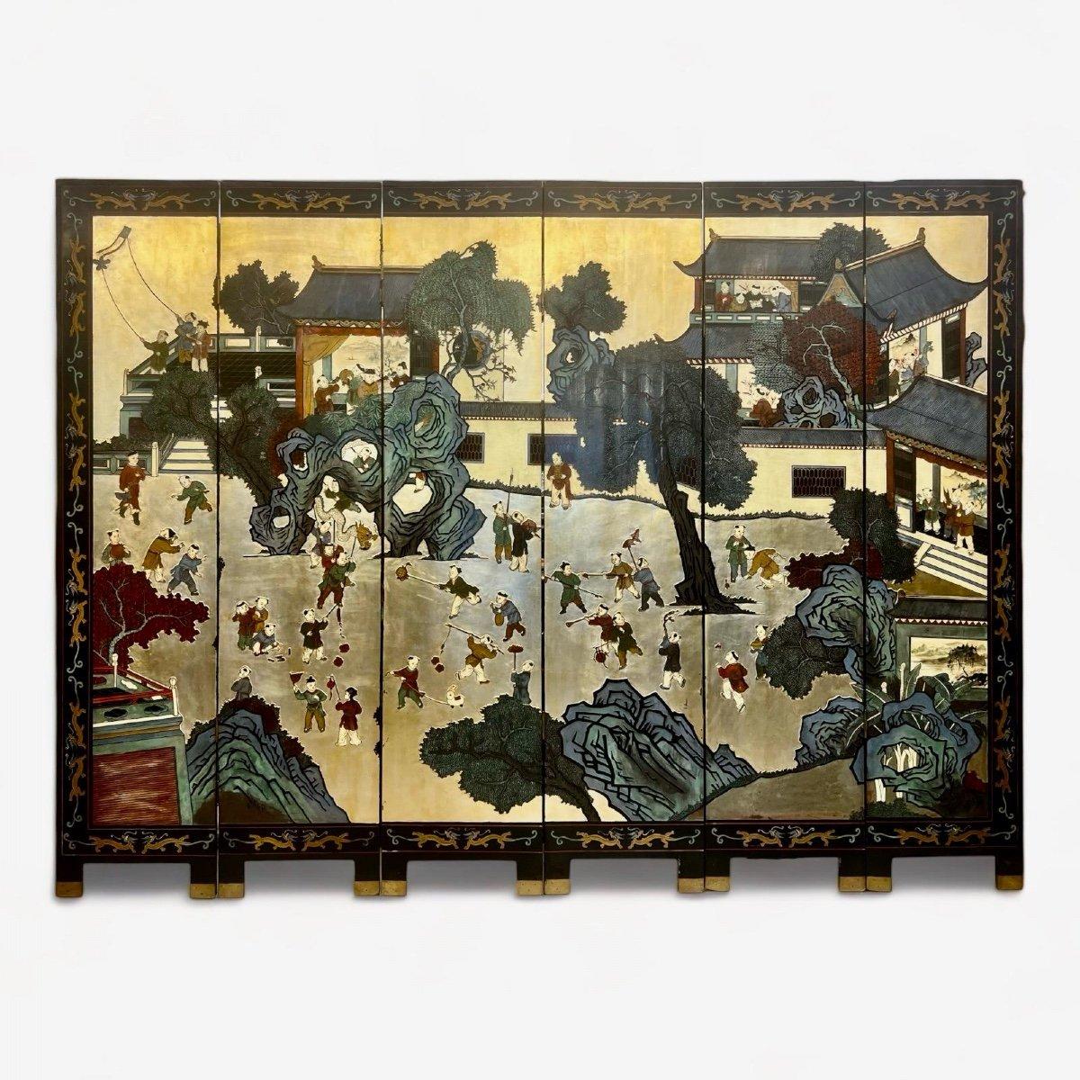 Dieser exquisite sechsfache Paravent aus chinesischem Koromandel-Lack aus dem frühen 20. Jahrhundert zeigt lebhafte Szenen von spielenden Kindern in einer traditionellen Dorflandschaft. Der Reichtum und die Fülle der Zeichen vor dem goldenen
