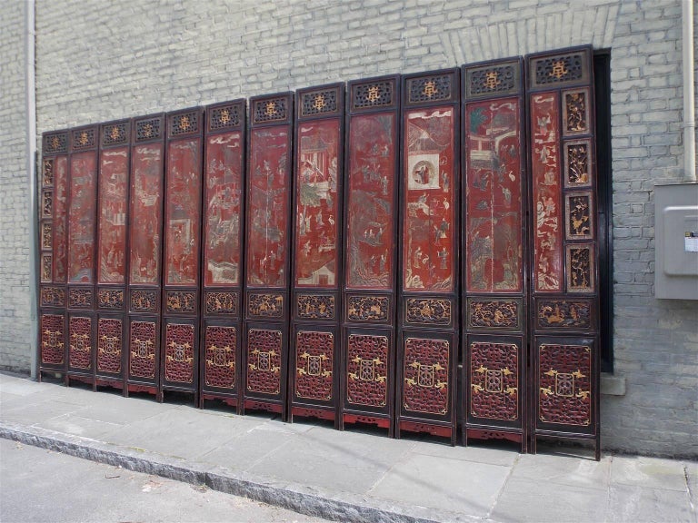 Chinese Coromandel figural red lacquer 12-panel screen depicting pagoda and landscape scenes, decorative gilt floral border panels, gilt carved lower panels, and reverse side depicting cranes, figural and floral motif. Screen rest on the original