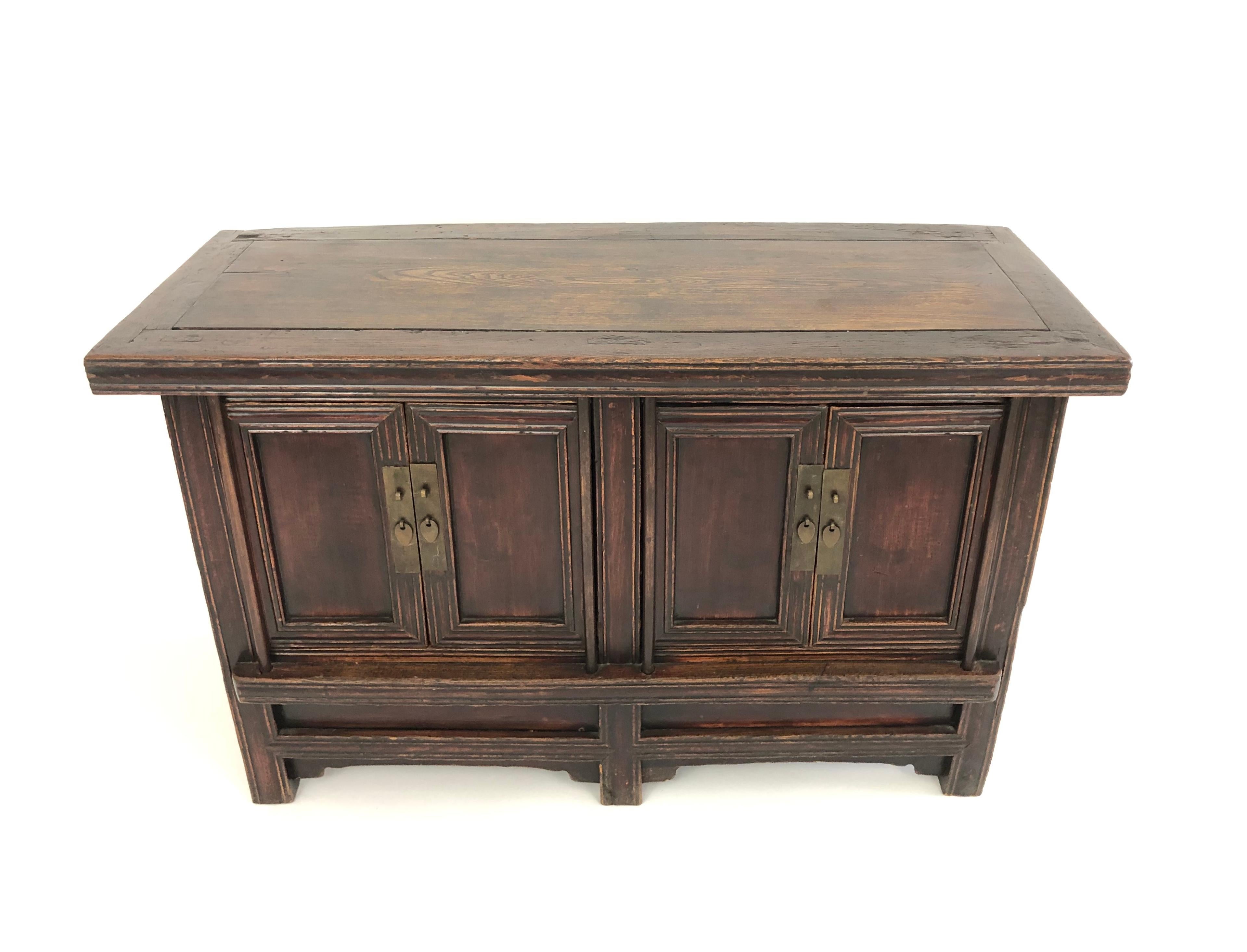 A Chinese country cabinet in elmwood, with beautifully rich old surface, good lines and clean proportions, of rectangular form, the rectangular top over two pairs of cupboard doors, with carved moldings and metal hardware pulls, enclosing shelves