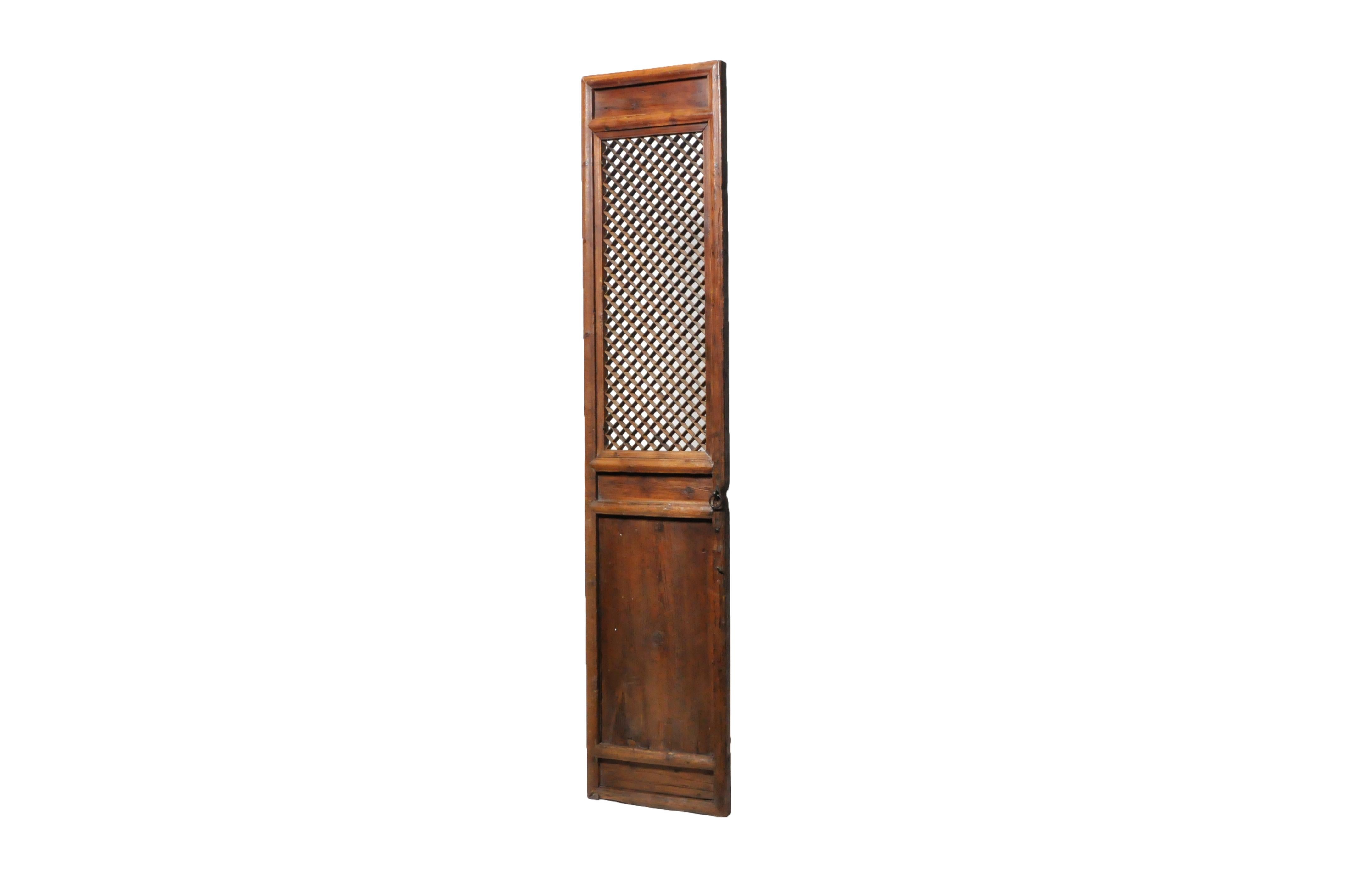 This tall and slender elm wood door panel was once part of a large series that surrounded a private courtyard in a Northern Chinese house. It features fine latticework and carved details. The patina is original with the addition of French polish and