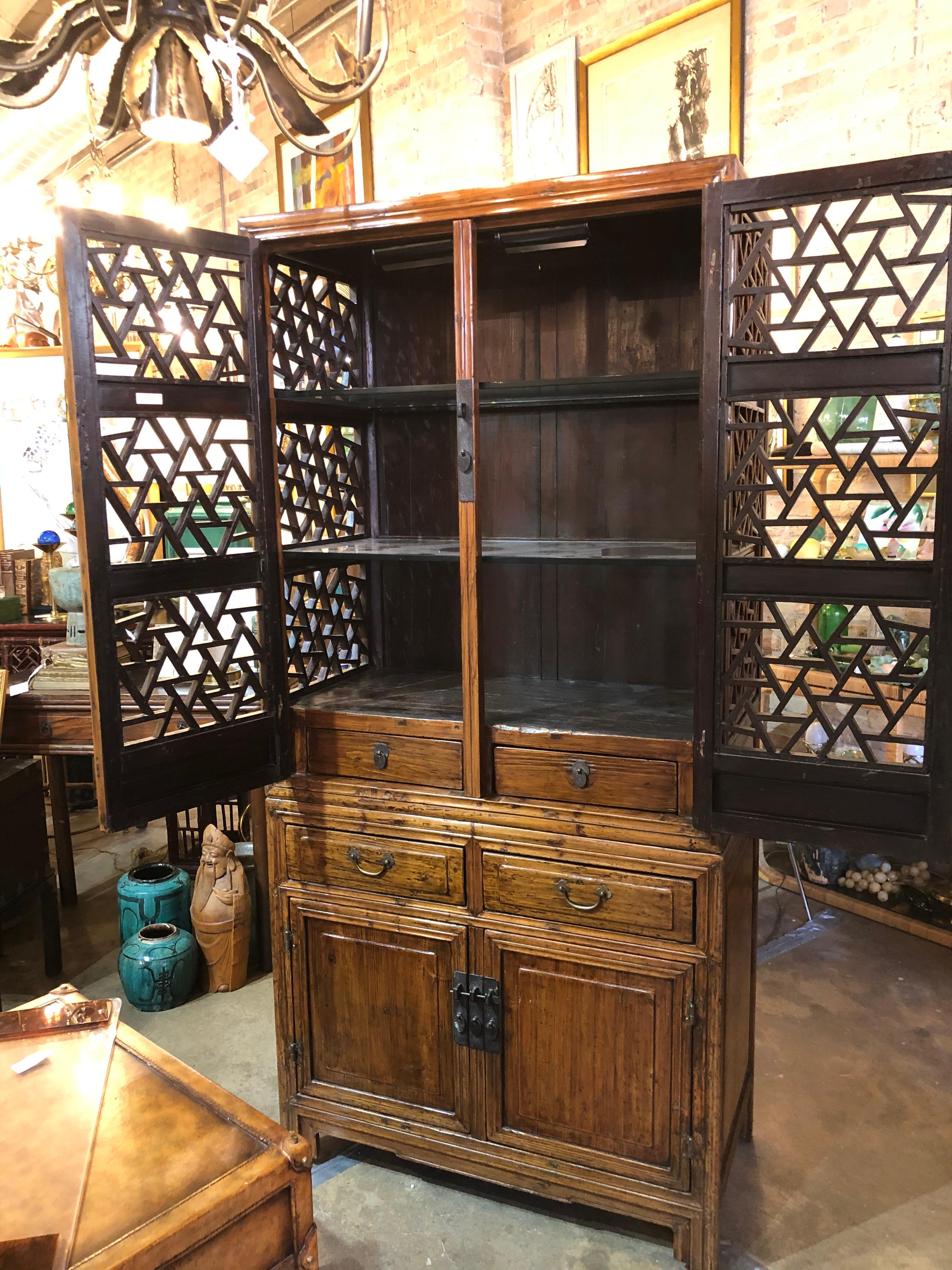 A 19th century Chinese elmwood cabinet having an open fretwork top over two drawers atop a two door cabinet. With lock and a beautiful patina!