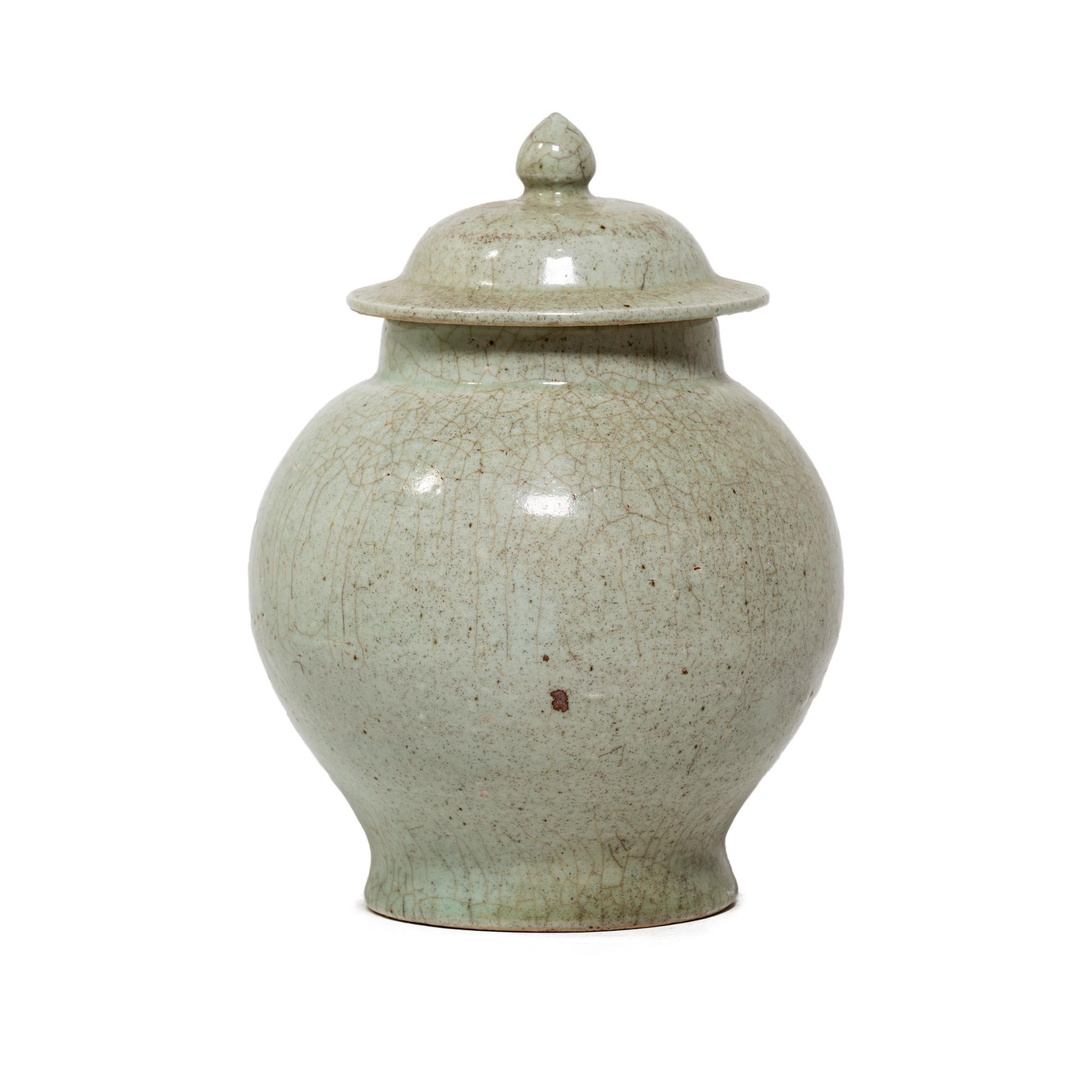 This round lidded vessel has a simple baluster jar form and a subdued celadon glaze finished with a richly crazed texture. Master ceramic artists in Zhejiang beautifully recreate the distinctive crackle glaze of traditional Guan and Ge ware,