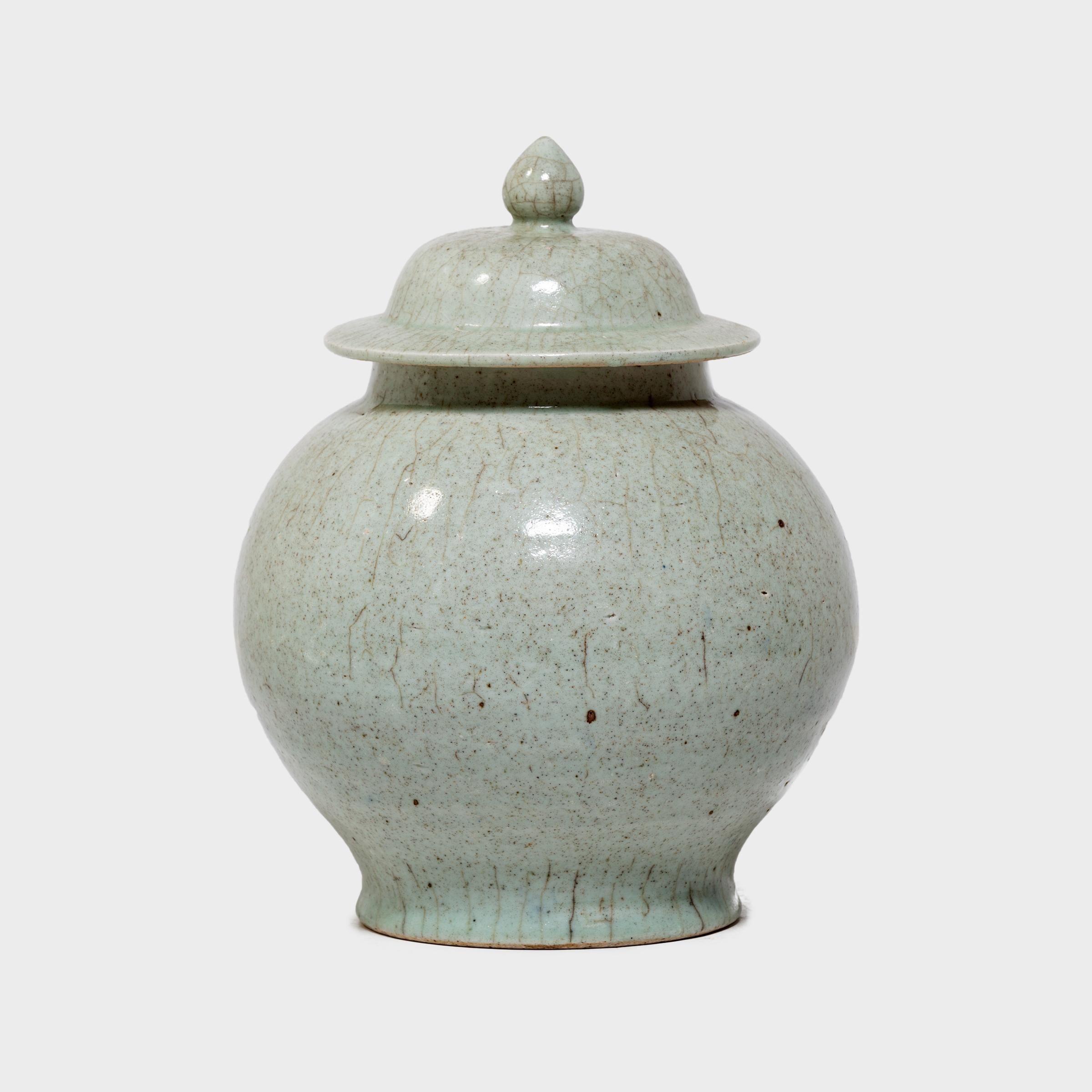 This round lidded vessel has a simple baluster jar form and a subdued celadon glaze finished with a richly crazed texture. Master ceramic artists in Zhejiang beautifully recreate the distinctive crackle glaze of traditional Guan and Ge ware,