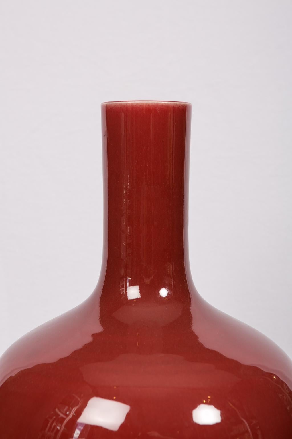 We are pleased to offer this large Chinese crimson long-neck vase dating to early 19th century. Evenly covered in a rich, warm, deep red glaze, the vase has a bulbous body that is elegantly potted. The crimson glaze, or 