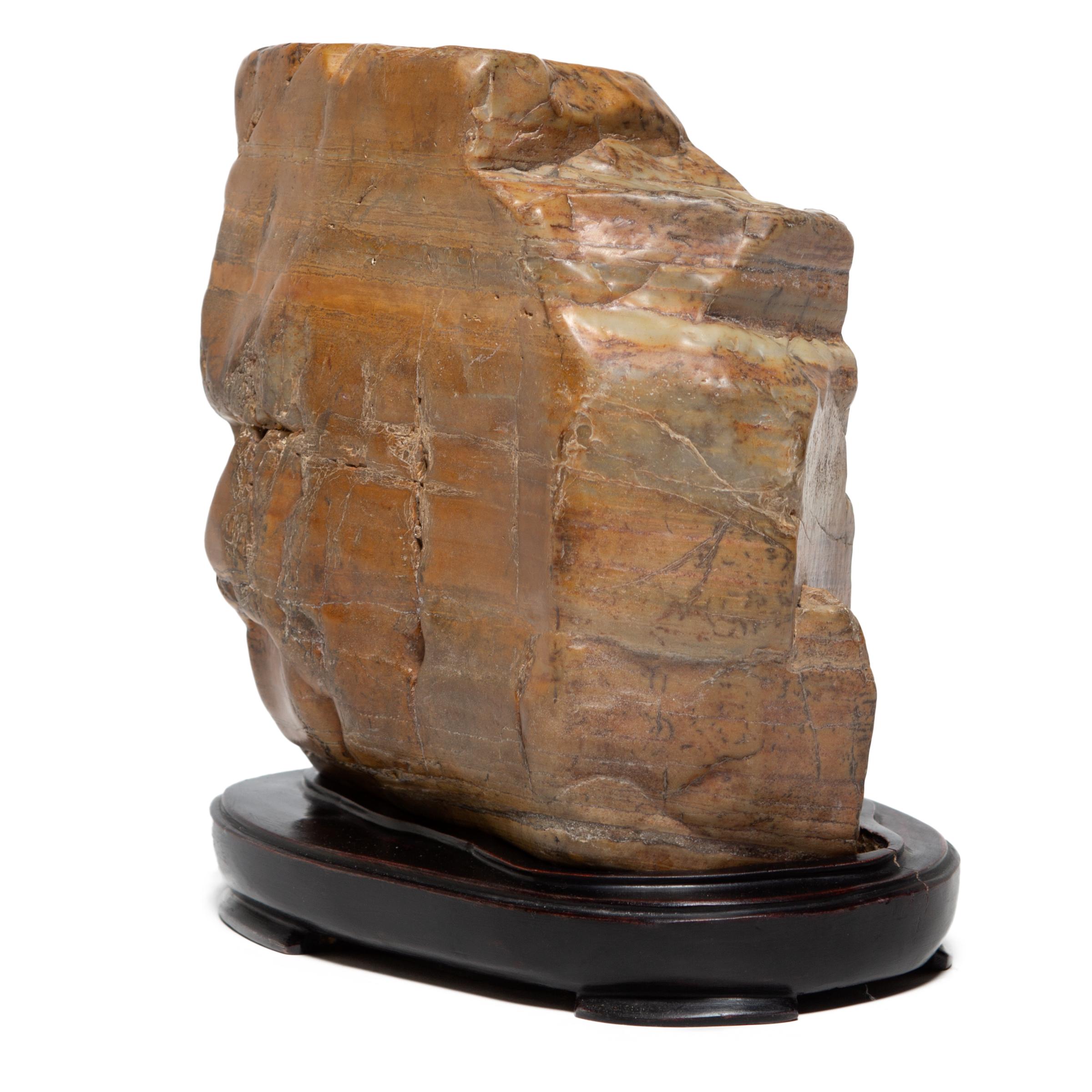 Elevated on a wood base, this mesmerizing dahua stone is displayed like a traditional scholars' rock. Meditating on the stone’s intriguing, irregular composition, the scholar found inspiration in the stone’s complex layering as a microcosm of the
