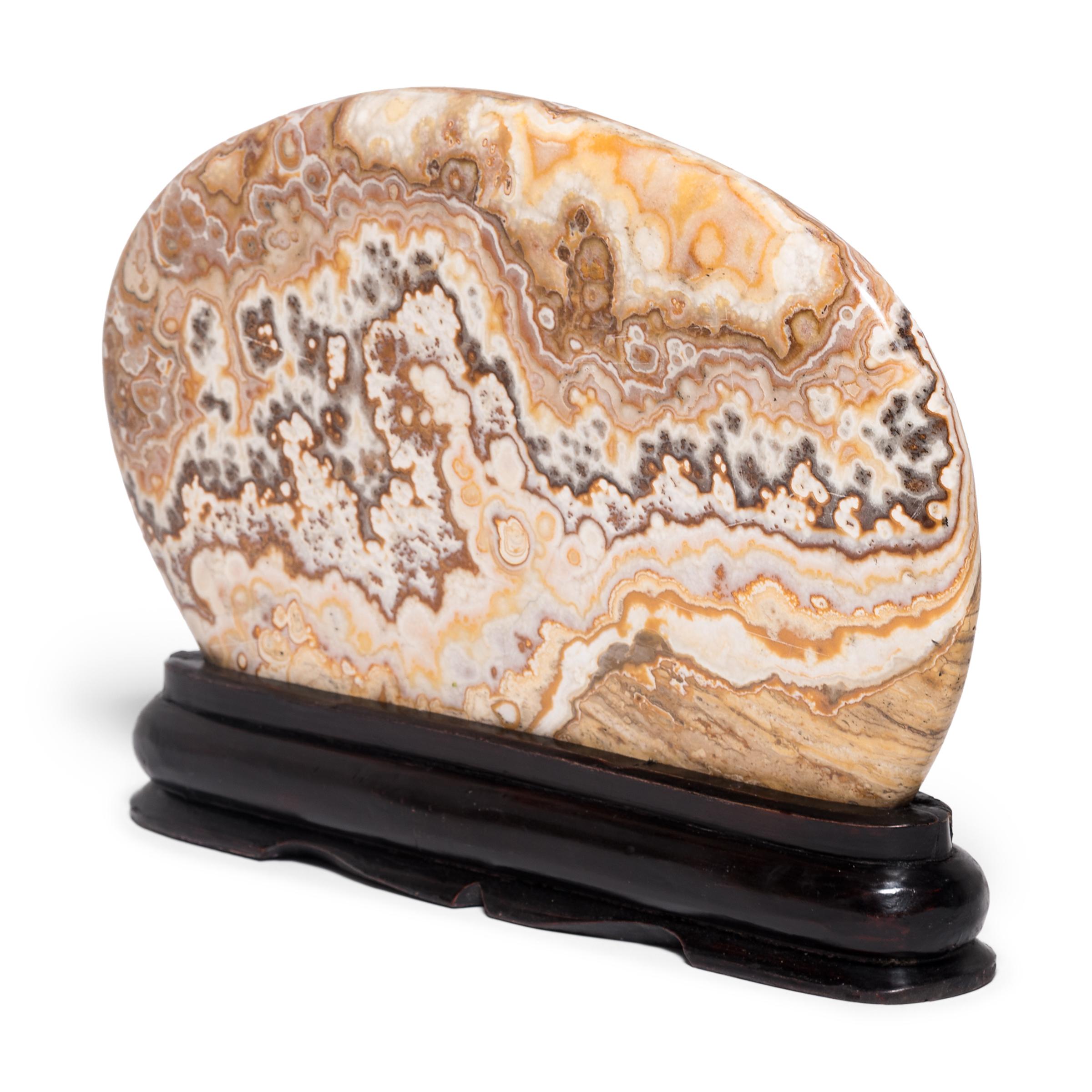 Elevated on a wood base, this mesmerizing danma stone is intricately patterned with swirling mineral deposits. Meditating on the stone’s intriguing, irregular composition, the scholar found inspiration in the stone’s complex layering as a microcosm