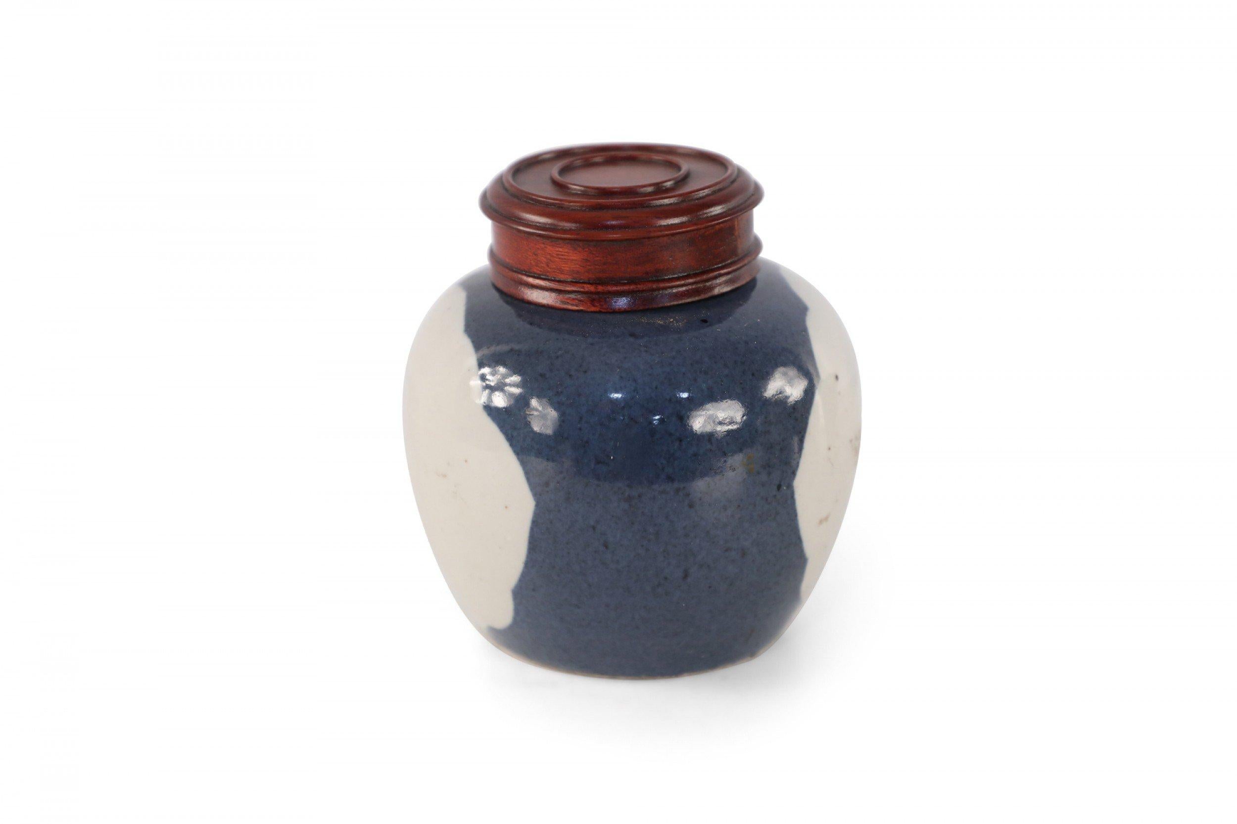 Chinese small porcelain watermelon jar with a dark blue background surrounding a white window pattern and turned wooden lid.
  