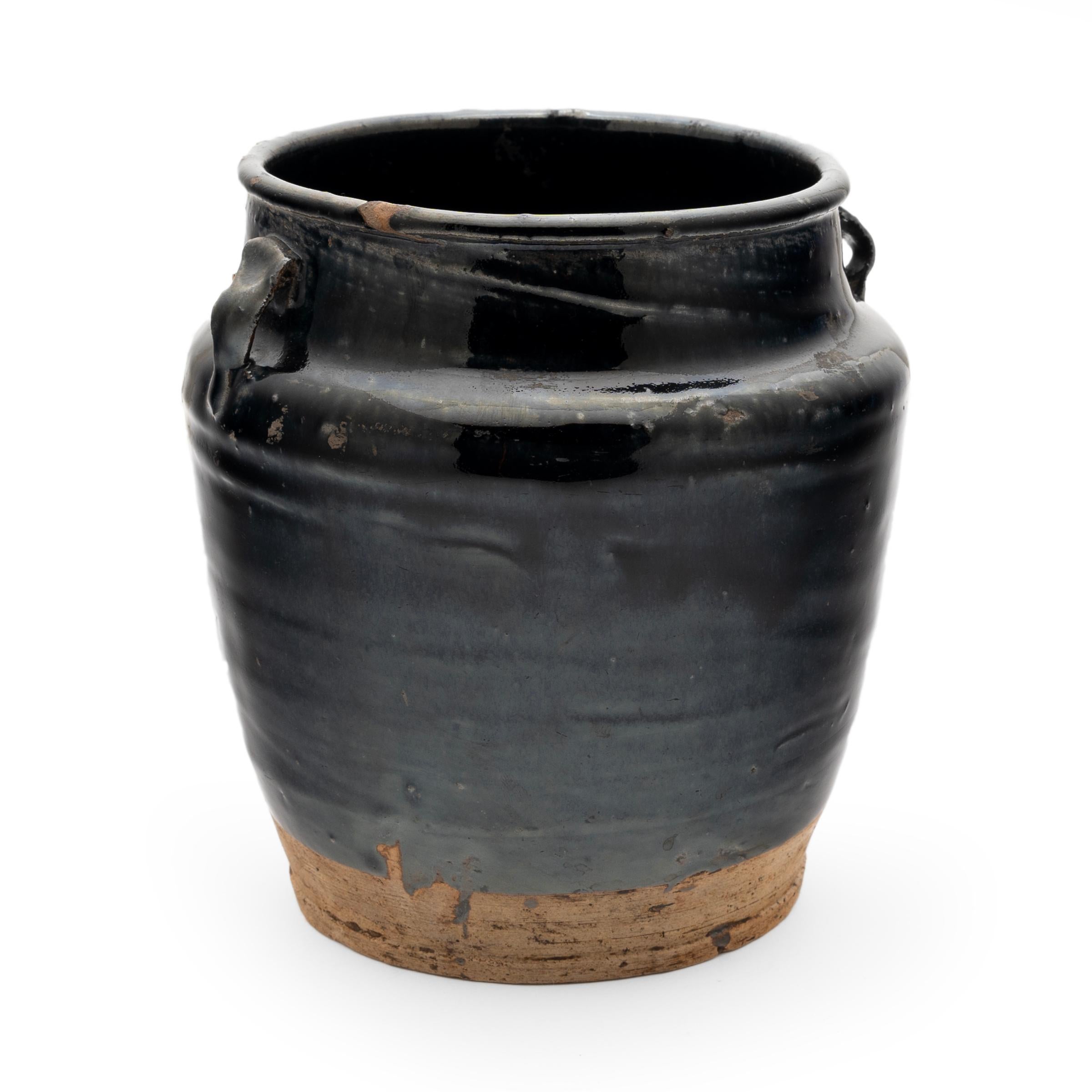 A cool, blue-black glaze coats the stout body of this early 20th-century terra cotta kitchen jar. As evidenced by the glazed interior, this wide-mouth jar was once used daily in a provincial Chinese kitchen for fermenting foods and condiments. The