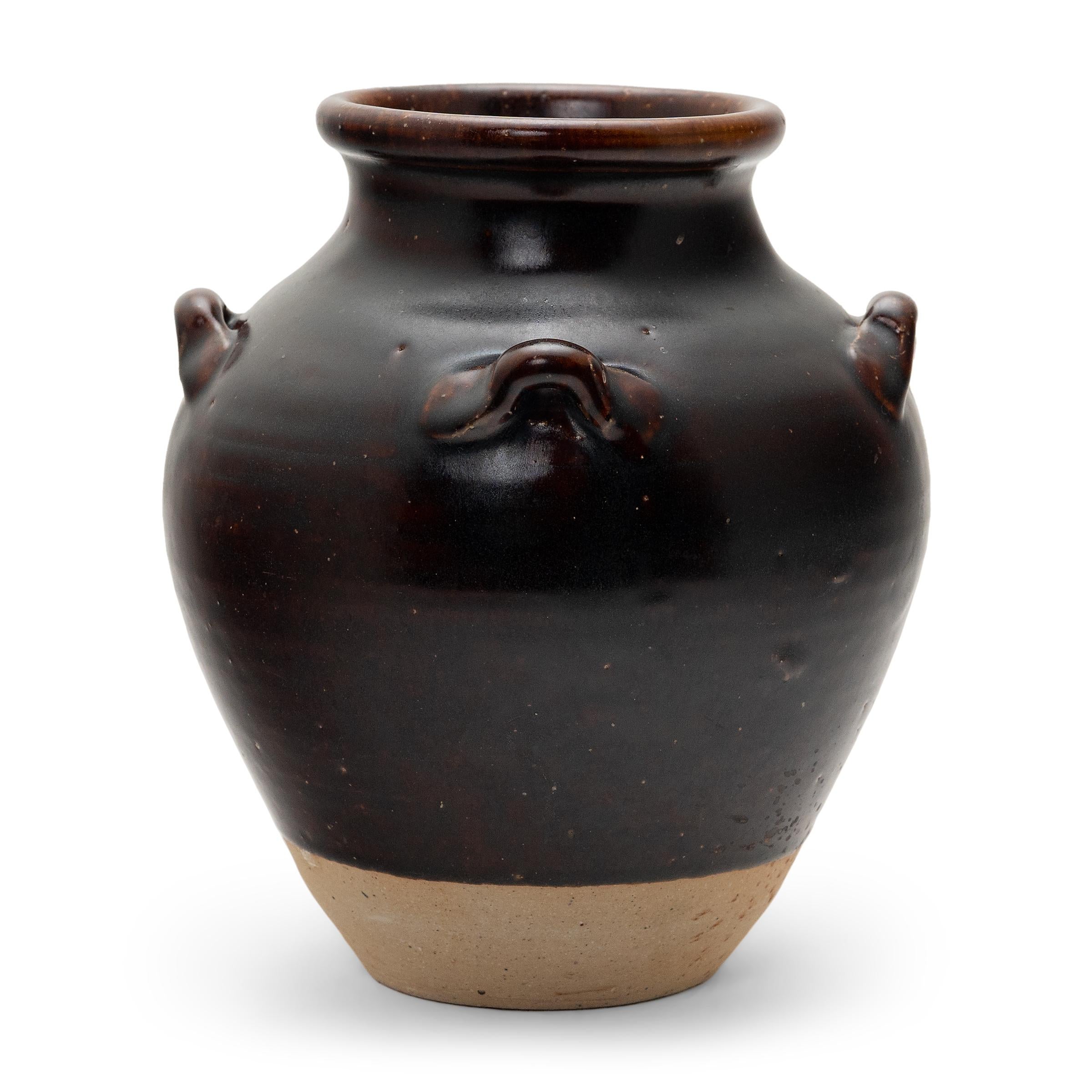 With a balanced profile and a lustrous, speckled glaze, this petite Chinese kitchen vessel is a charming example of handcrafted pottery. As evidenced by its interior glaze, the small jar was originally used for storing liquids such as rice wine,