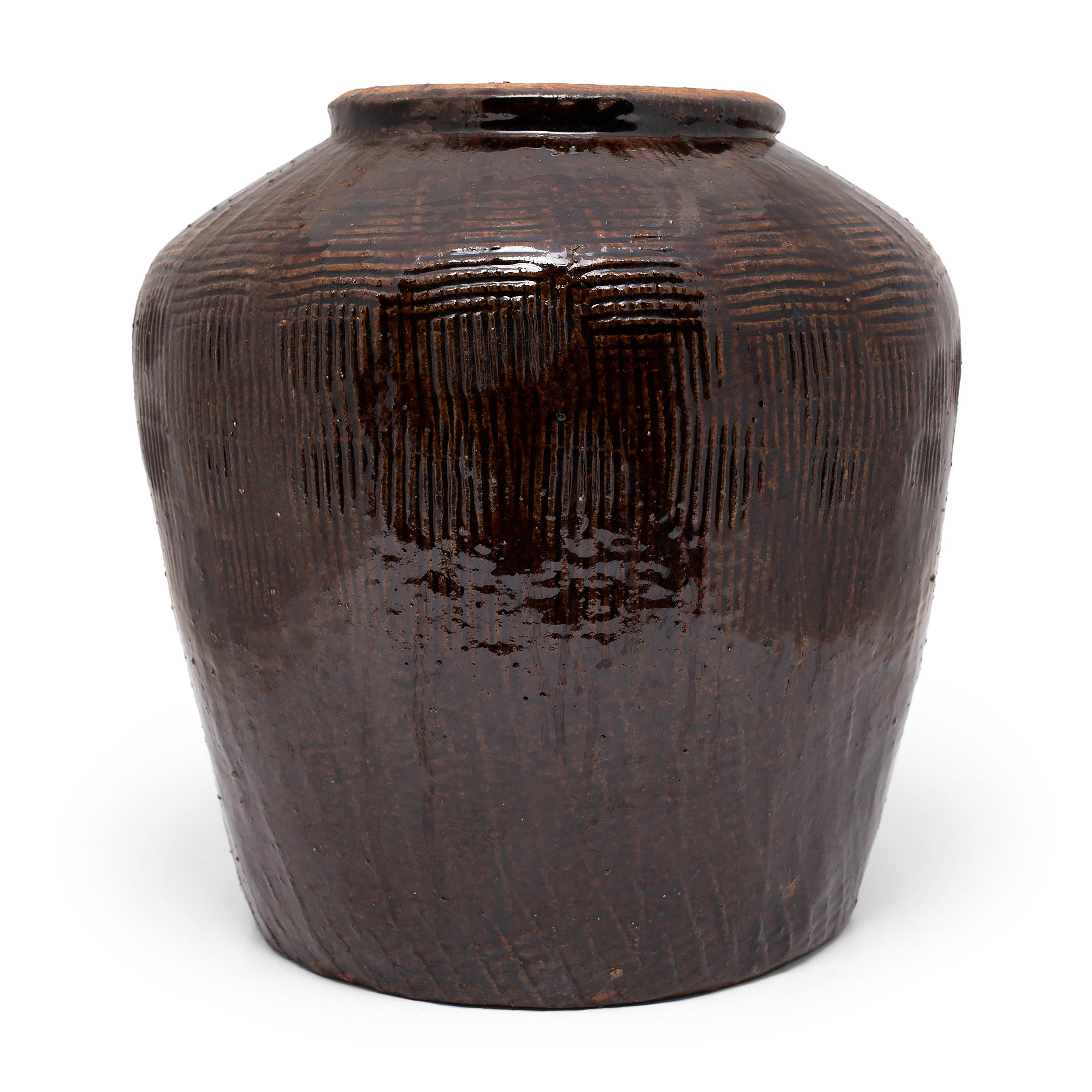 Originally used for fermenting foods and condiments in a provincial Chinese kitchen, this 19th century terracotta jar is coated inside and out with a rich, dark brown glaze. The jar has a slightly tapered form with a wide base, high shoulders, and a