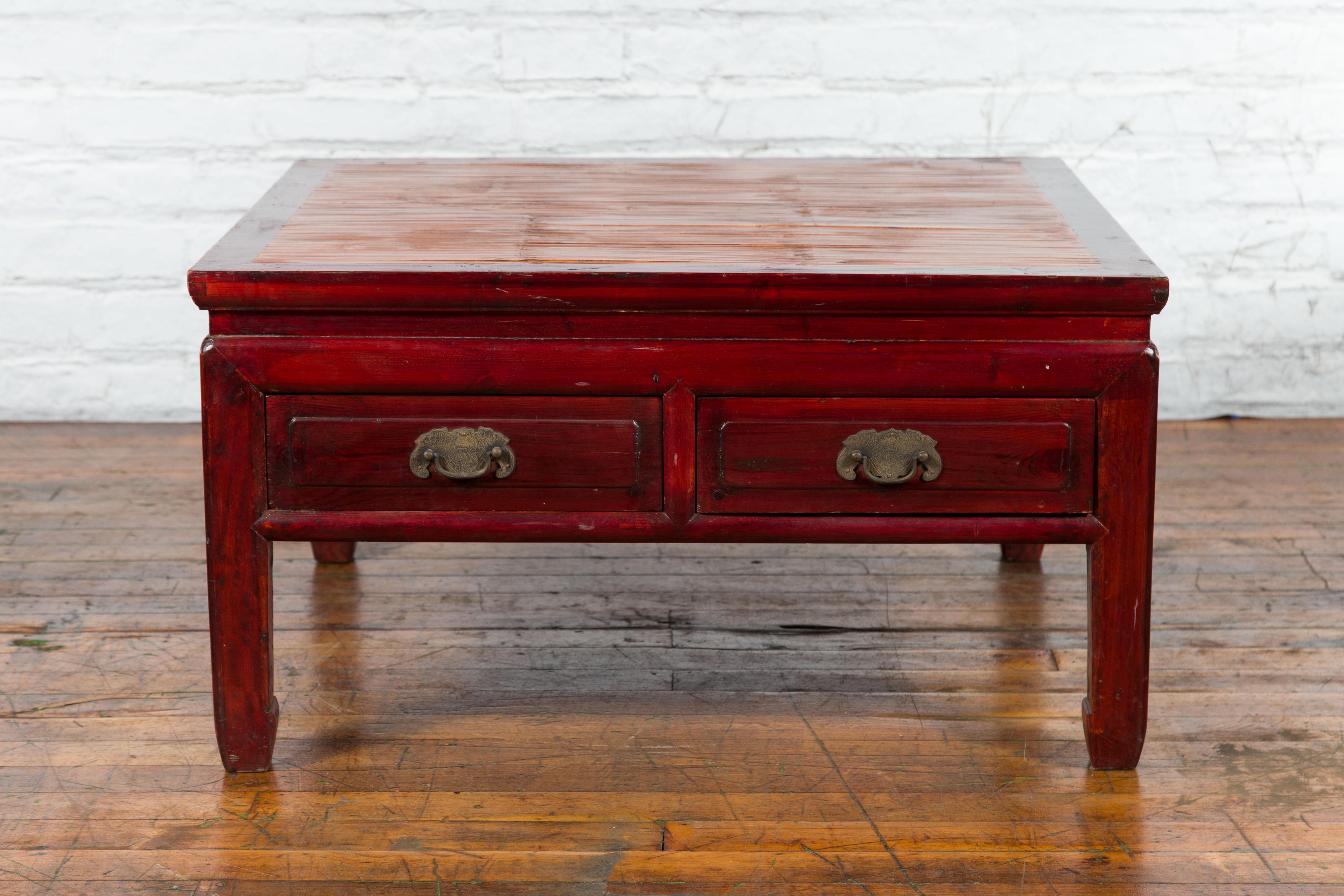 A Chinese coffee table from the early 20th century with bamboo top and long drawers. Created in China during the early years of the 20th century, this dark red lacquered coffee table features a square bamboo top sitting above two long drawers fitted