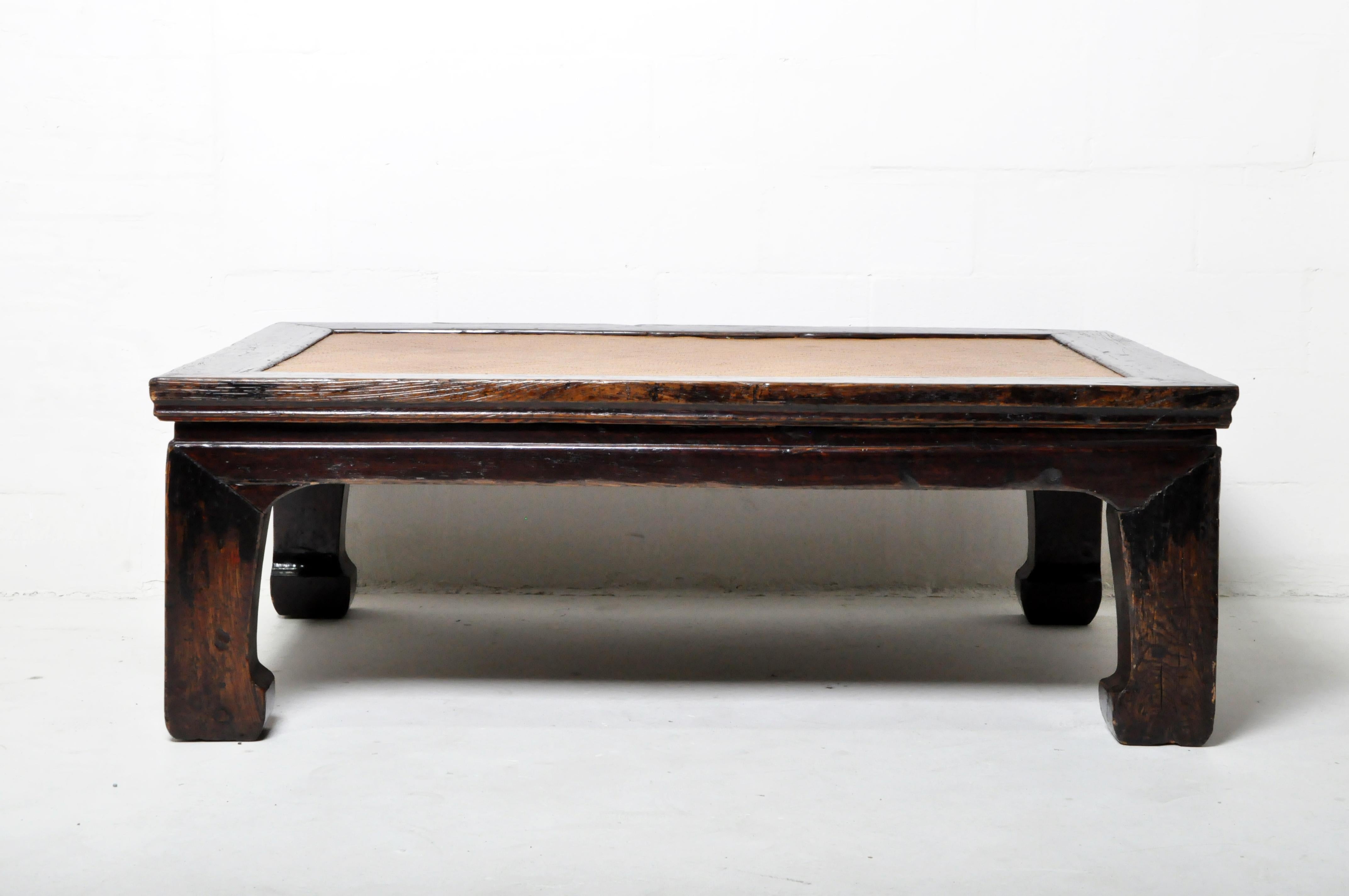 This classic northern Chinese daybed has been cut down in length to make a unique coffee table. The finely woven cane top is supported by tautly stretched jute cord webbing, using the original holes in the frame. The heavy elmwood legs and top frame