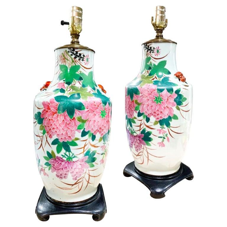 Chinese Deco Chrysanthemum Porcelain Lamp, Hollywood Regency, Early 20th Century.   Hand painted. Floral front, lion handles and calligraphy on back. This listing is for a single table lamp. Measurement to top of socket approx. 21”. Lampshade not
