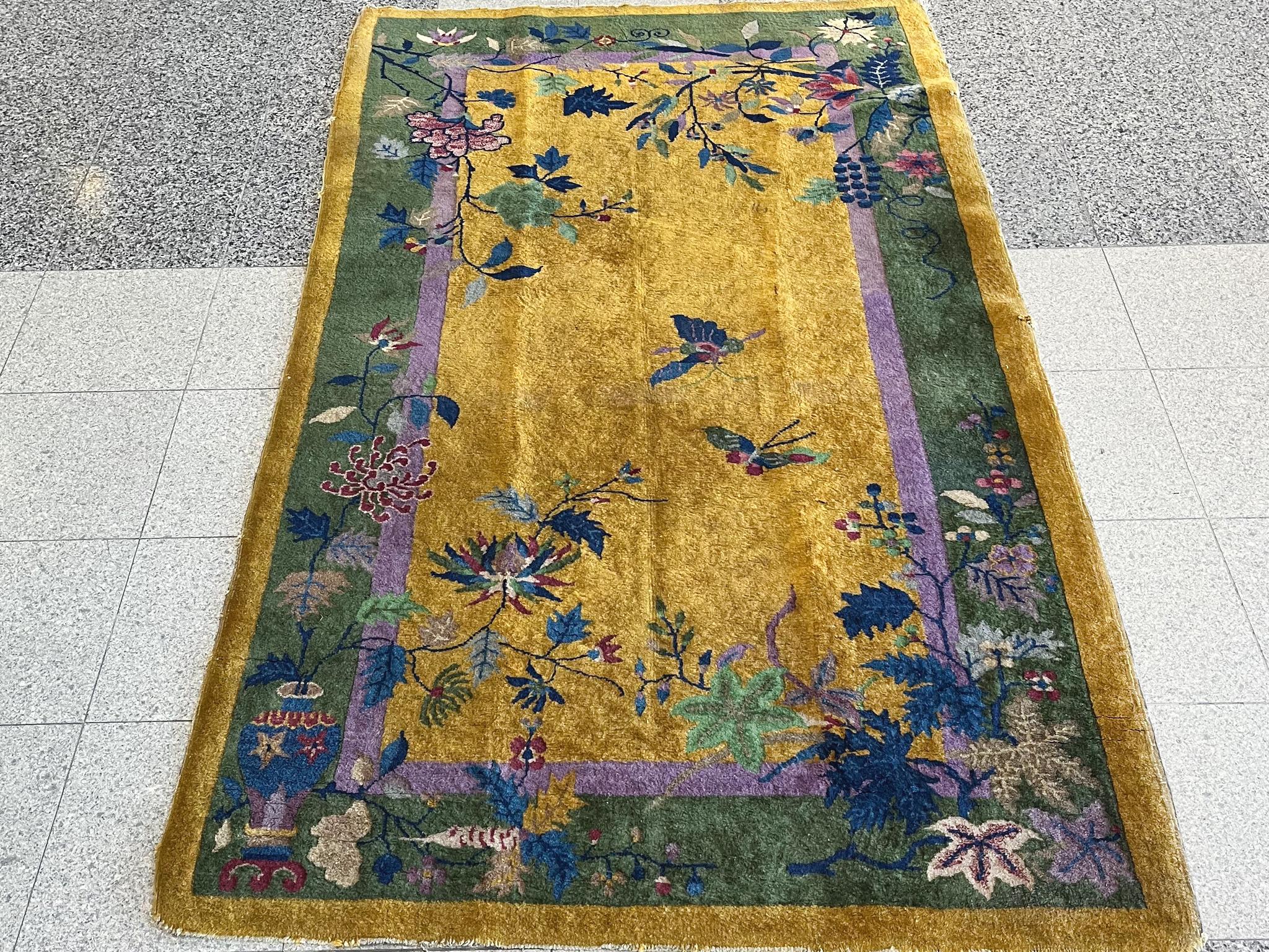 Tapis déco chinois tissé à la main dans les années 1930, avec une palette vibrante de verts, de pourpres et de bleus disposés dans un motif de fleurs et de vignes sur un champ d'oliviers bronze.

Dimensions :
6'9