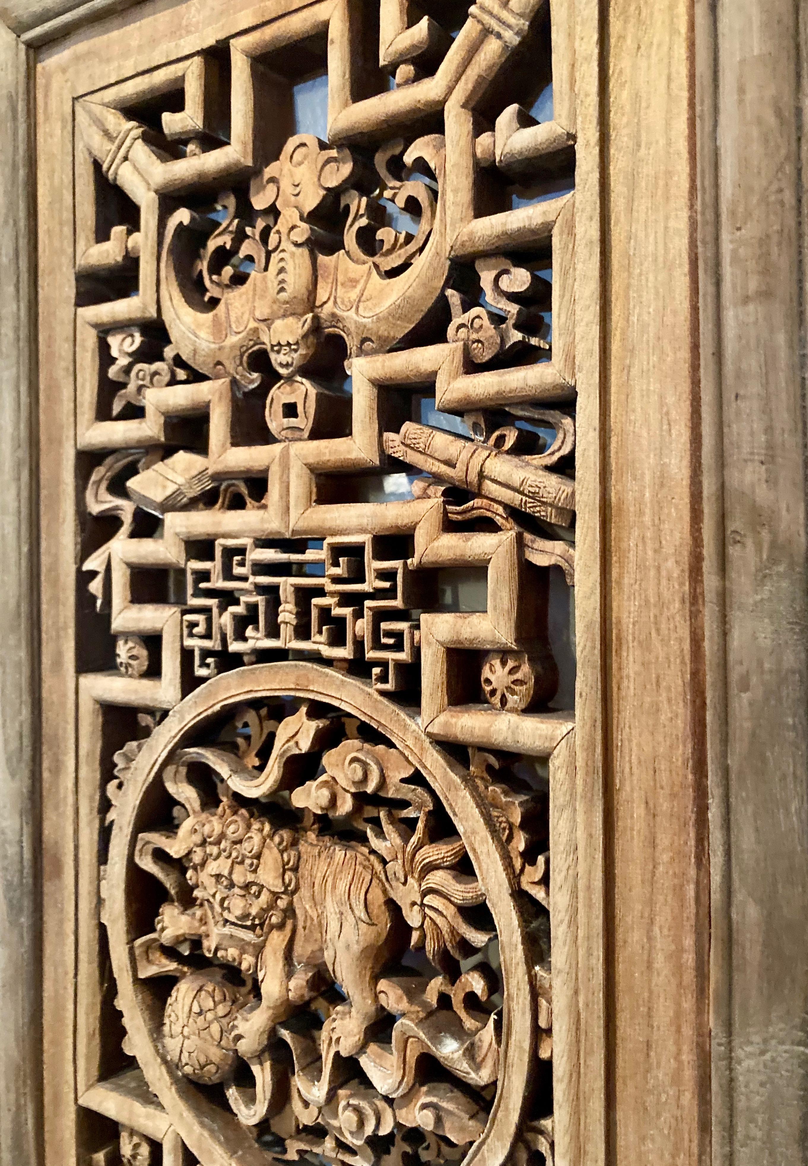 The intricate design in this framed panel includes a circular center carving with a mythical creature, and a surrounding bat motif.