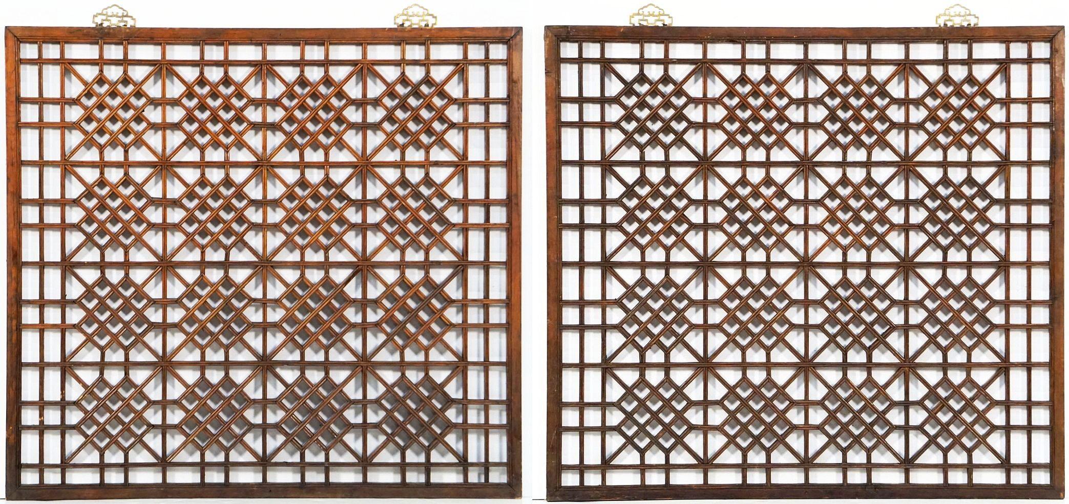 A fine set of Chinese decorative lattice-work wood panels or window screens of patinated pine from the early 20th century - each panel featuring an open geometric lattice pattern design of individual wood segments in a square frame with a light
