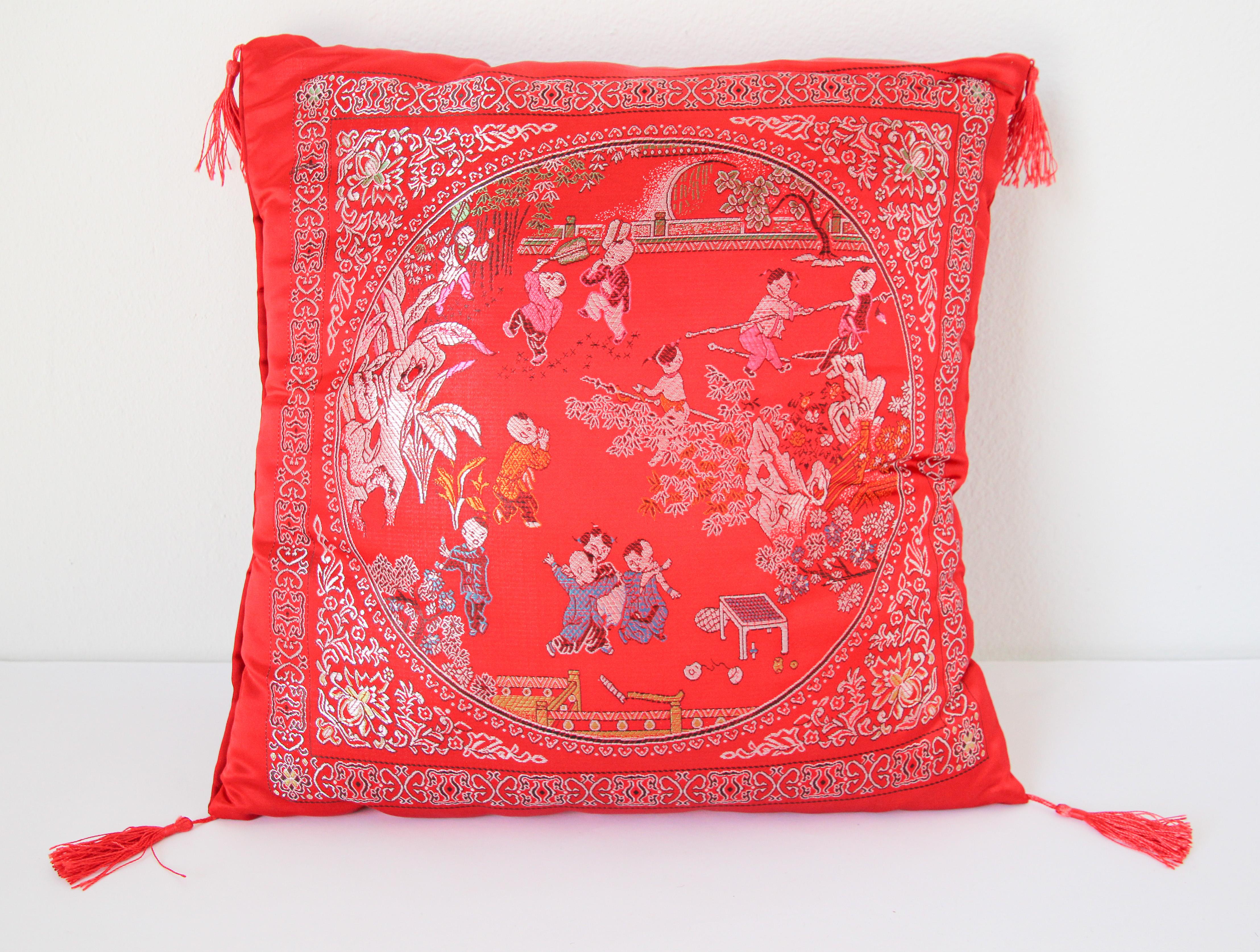 Asian decorative throw pillow with fringes and red tassels.
Luxury silk in red with scene of kids playing outdoor in traditional Chinese costumes.