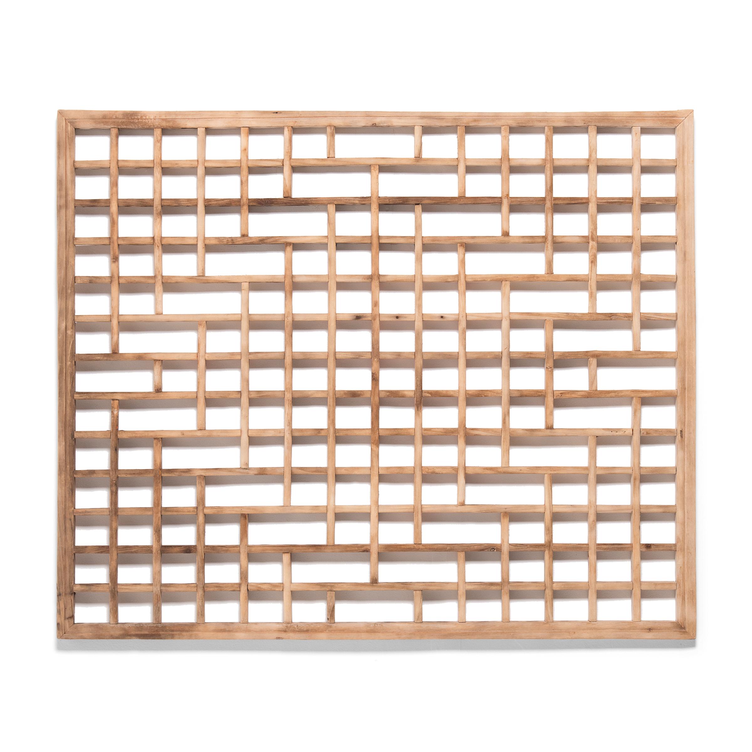 This early 20th century lattice window panel likely originated in a northern Chinese home with neutral and balanced interiors. The geometric lattice pattern is linear and open, and was designed to allow light and air into a room while maintaining