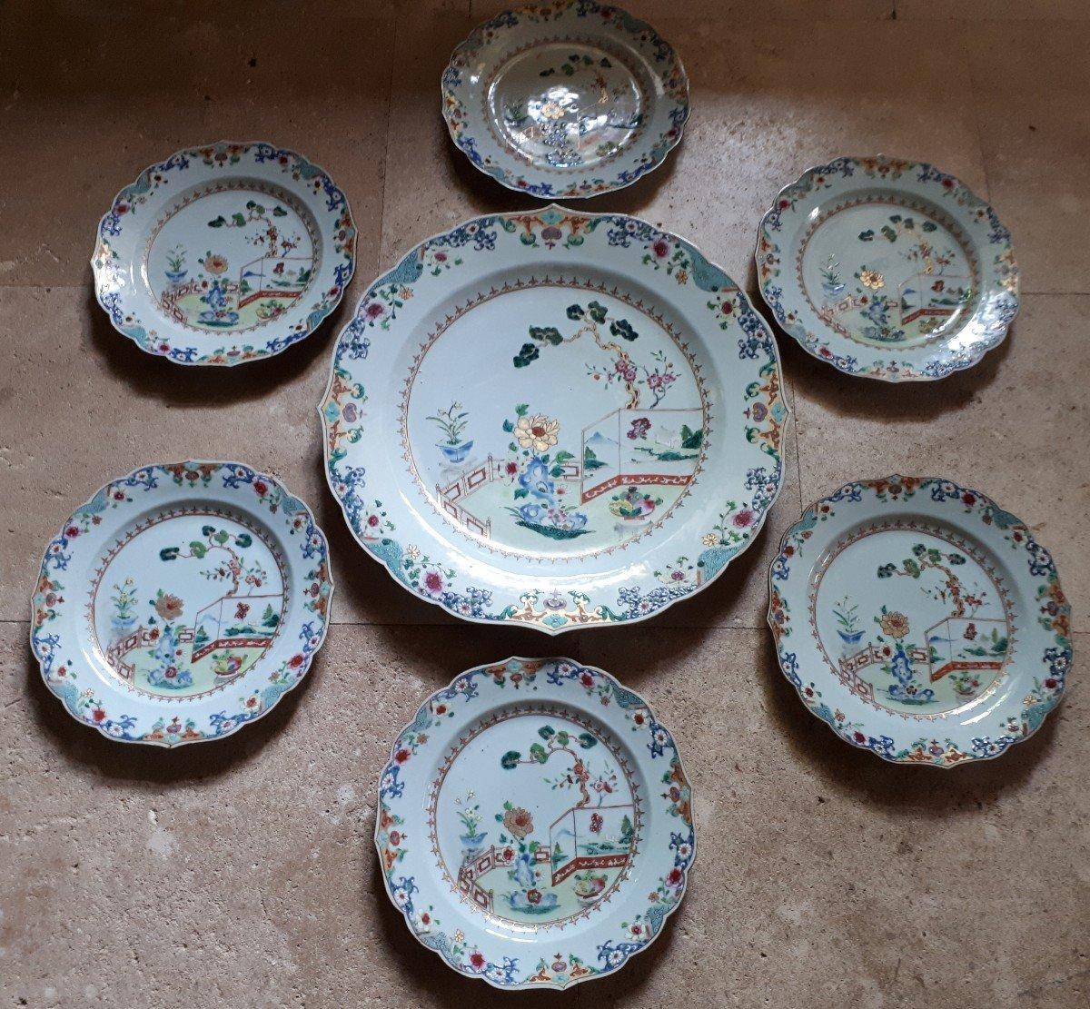 A dish and six scalloped plates in Famille rose porcelain with garden decorations. The dish is in perfect condition. Chips on the reverse of two plates. Dish diameter 38 cm, plates 23 cm. China, first half of the 18th century. Rare in this condition