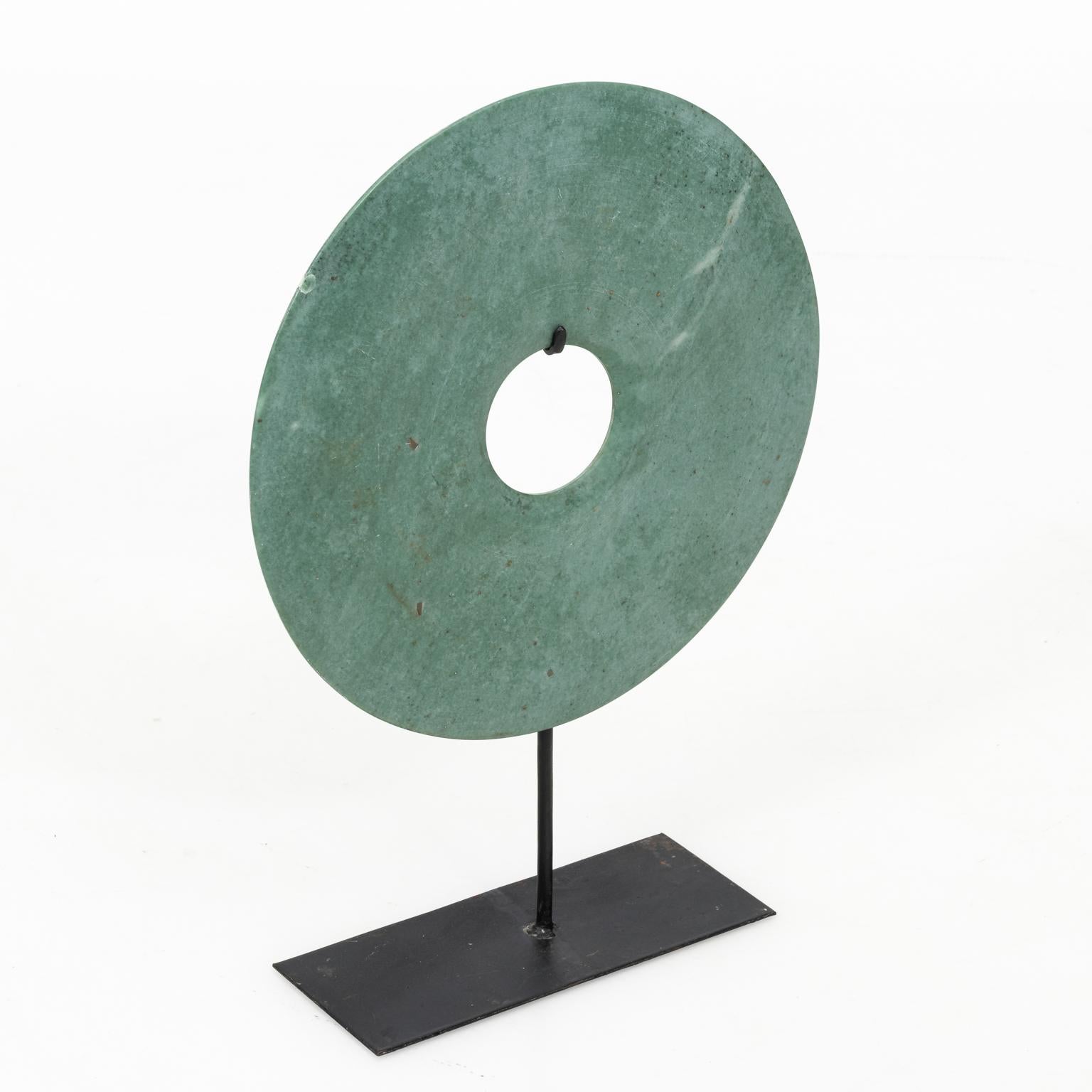 Decorative abstract Asian stone disk art on black metal stand.