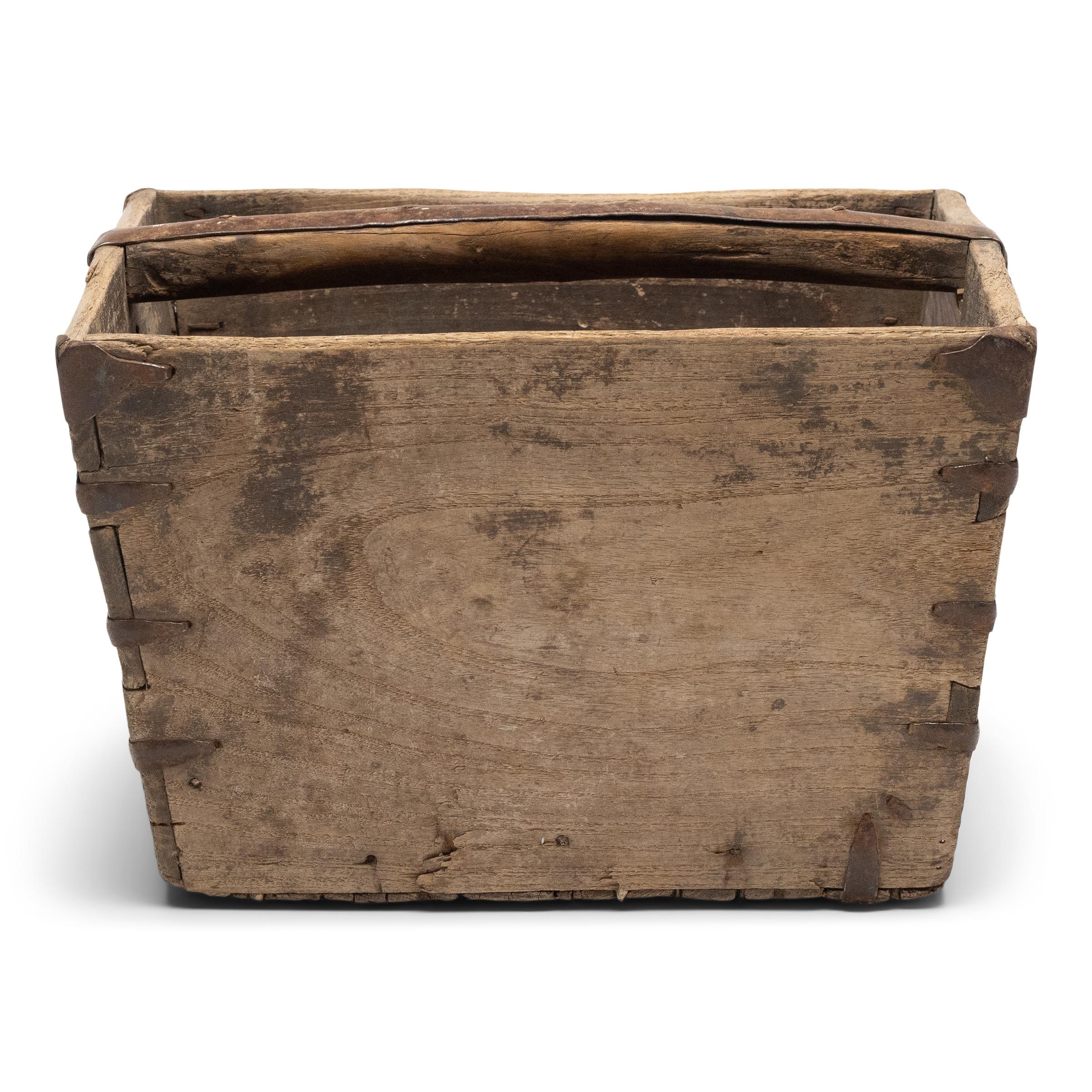 This rustic container was made over a hundred years ago to measure and hold a dou of rice, a traditional Chinese unit of volume. The rice measure has a square form with tapered sides, handcrafted of elm with dovetail joinery, iron staple