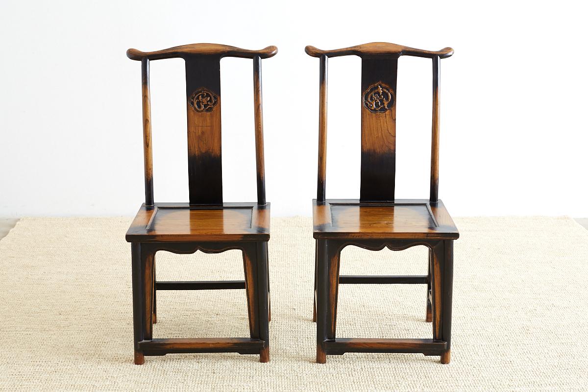 Stunning pair of Chinese yoke back officials hat chairs featuring a carved dragon motif backsplat. These carved chairs have a gorgeous lacquer finish that is distressed and worn with a craquelure patina. Beautifully made with old world joinery and a