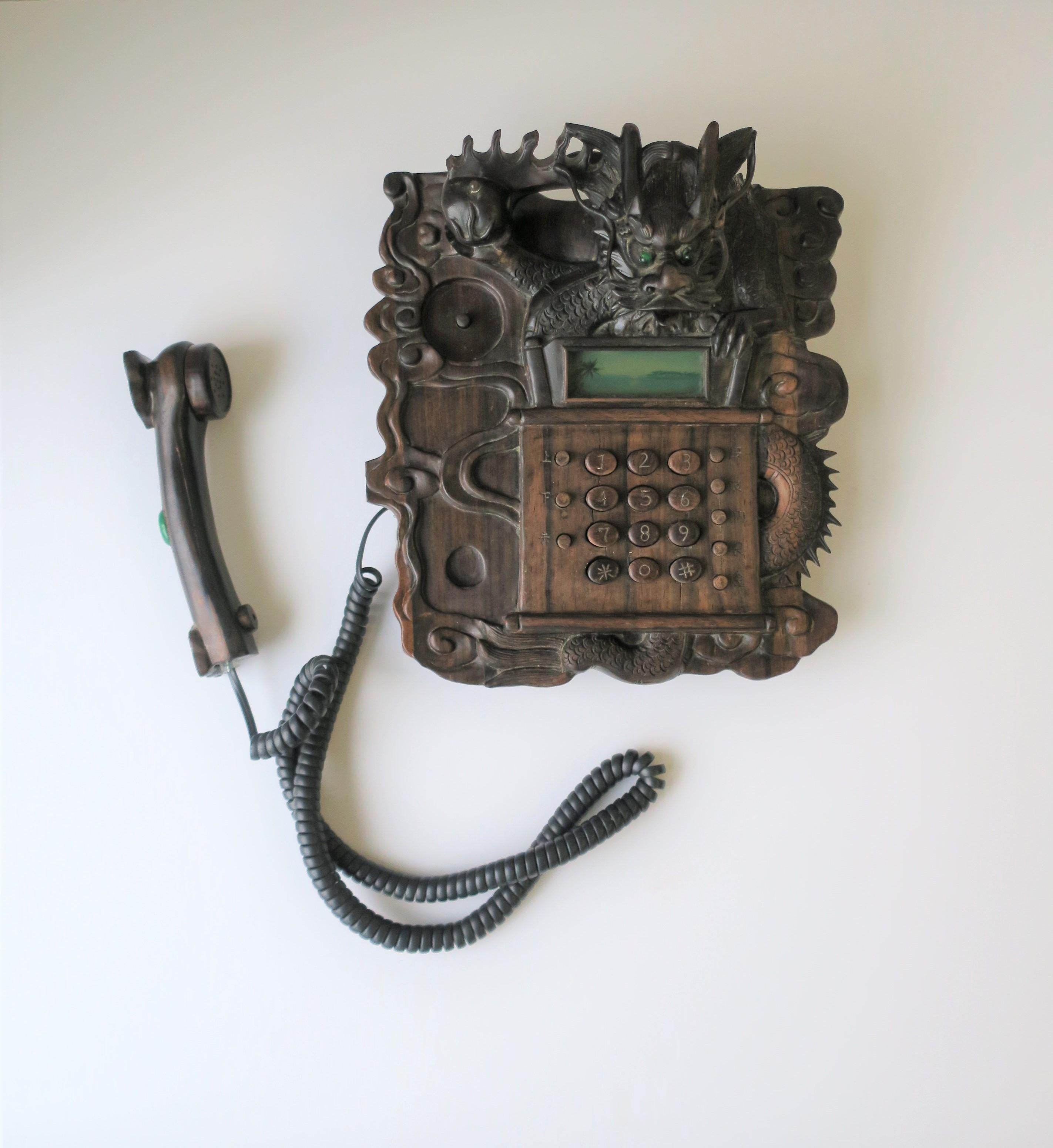 A very beautiful, rare, and exotic Chinese dragon landline telephone, circa 1980s-1990s. Phone is a hard carved wood with all the details of a dragon (claws, tongue, horns, tail, etc.) Phone handle has a beautiful oval piece of polished emerald
