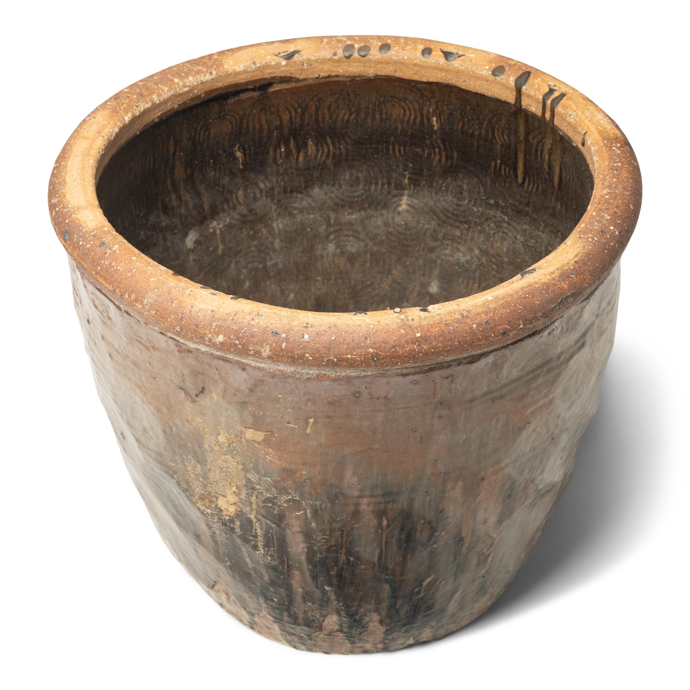 Originariamente utilizzato per mettere in salamoia gli alimenti, questo grande vaso di terracotta è stato scolpito nella provincia cinese dello Shanxi quasi due secoli fa, modellato a mano in grande scala e con una struttura wabi-sabi. Il