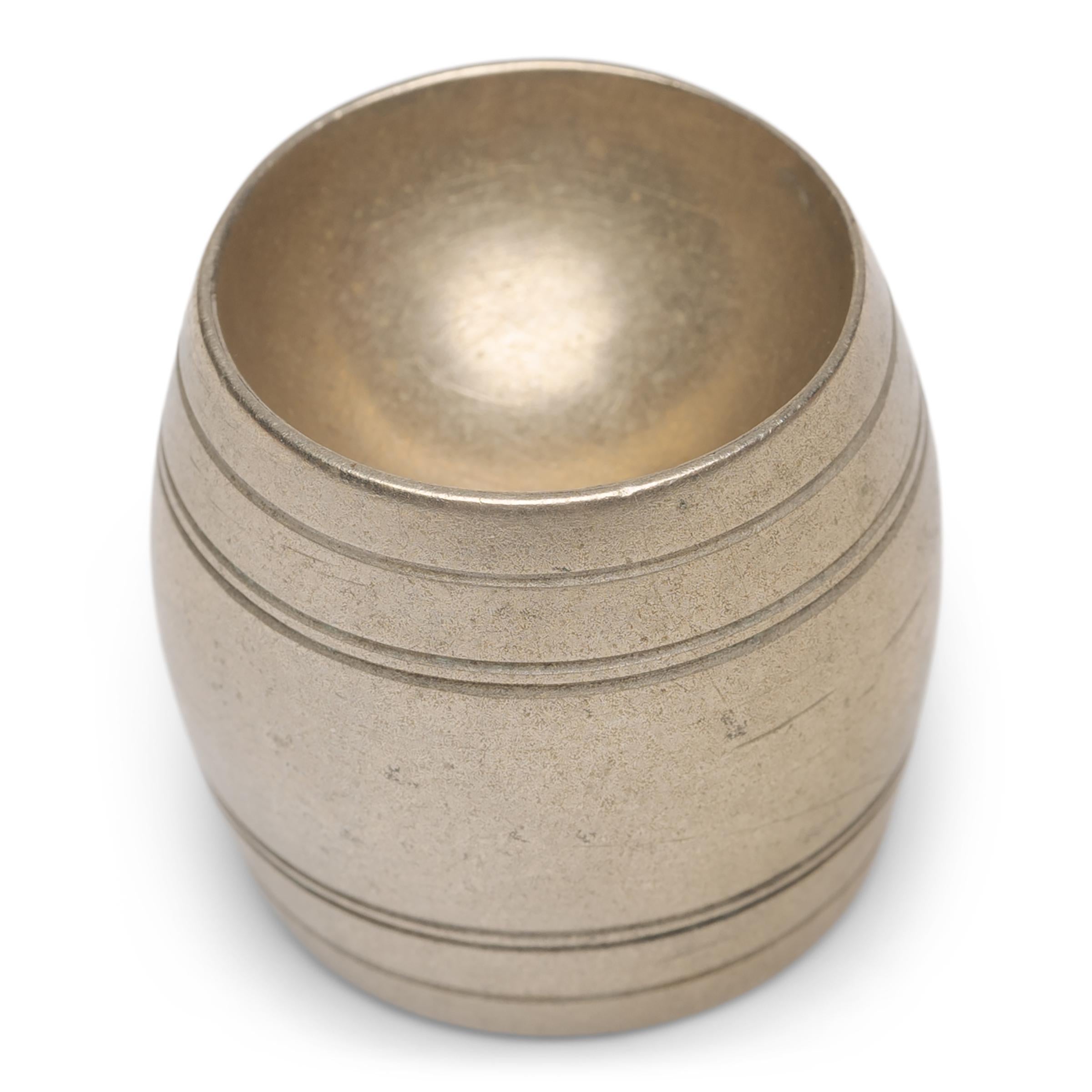 This unusual, barrel-form object was originally one of the many accessories that comprised an opium smoker's kit. Formed of brass with a copper lining, the small tool is known by collectors as a 
