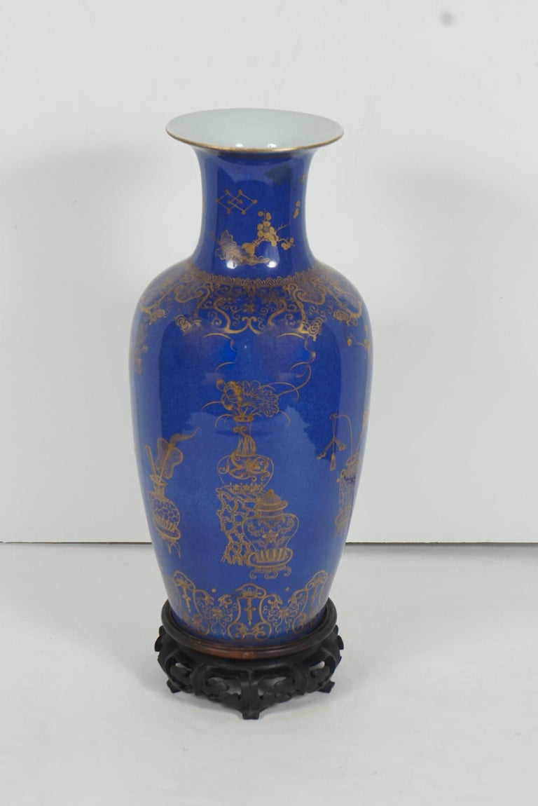 This fine early 19th century Chinese powder blue glazed gilt overlay vase has a very beautiful and dynamic mottled glaze. The gilded overlay consists of designs of censors and vases that contain fans, scrolls, ruyi scepters flowering prunus branches