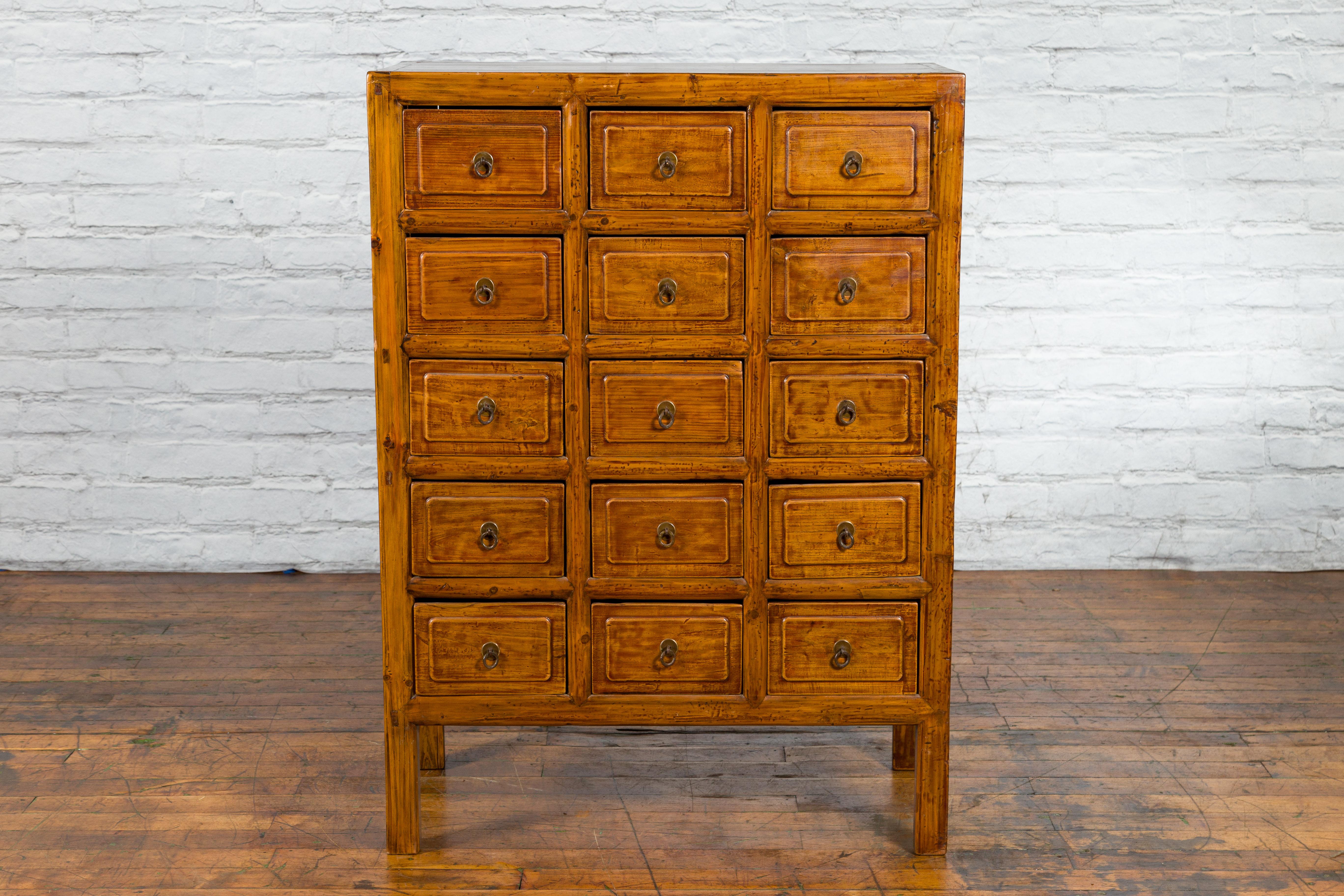 A Chinese apothecary cabinet from the early 20th century, with 15 drawers, light brown finish and straight legs. We currently have a pair available, however we are selling them individually $4,400 each. Created in China during the early years of the