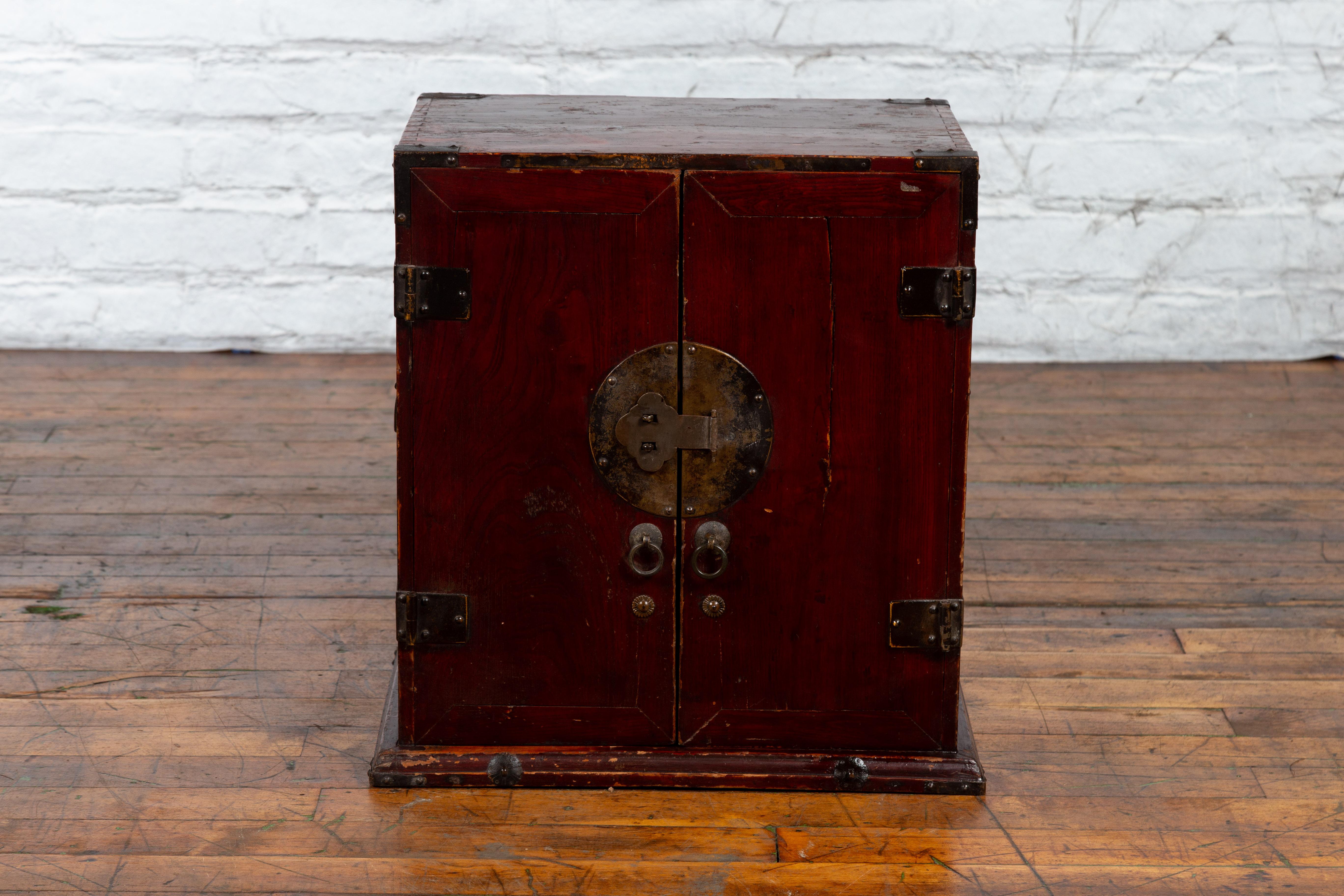 An antique Chinese dark red carrying chest from the early 20th century, with side handles. Created in China during the early years of the 20th century, this carrying chest features a linear silhouette perfectly complimented by a dark red patina. Two