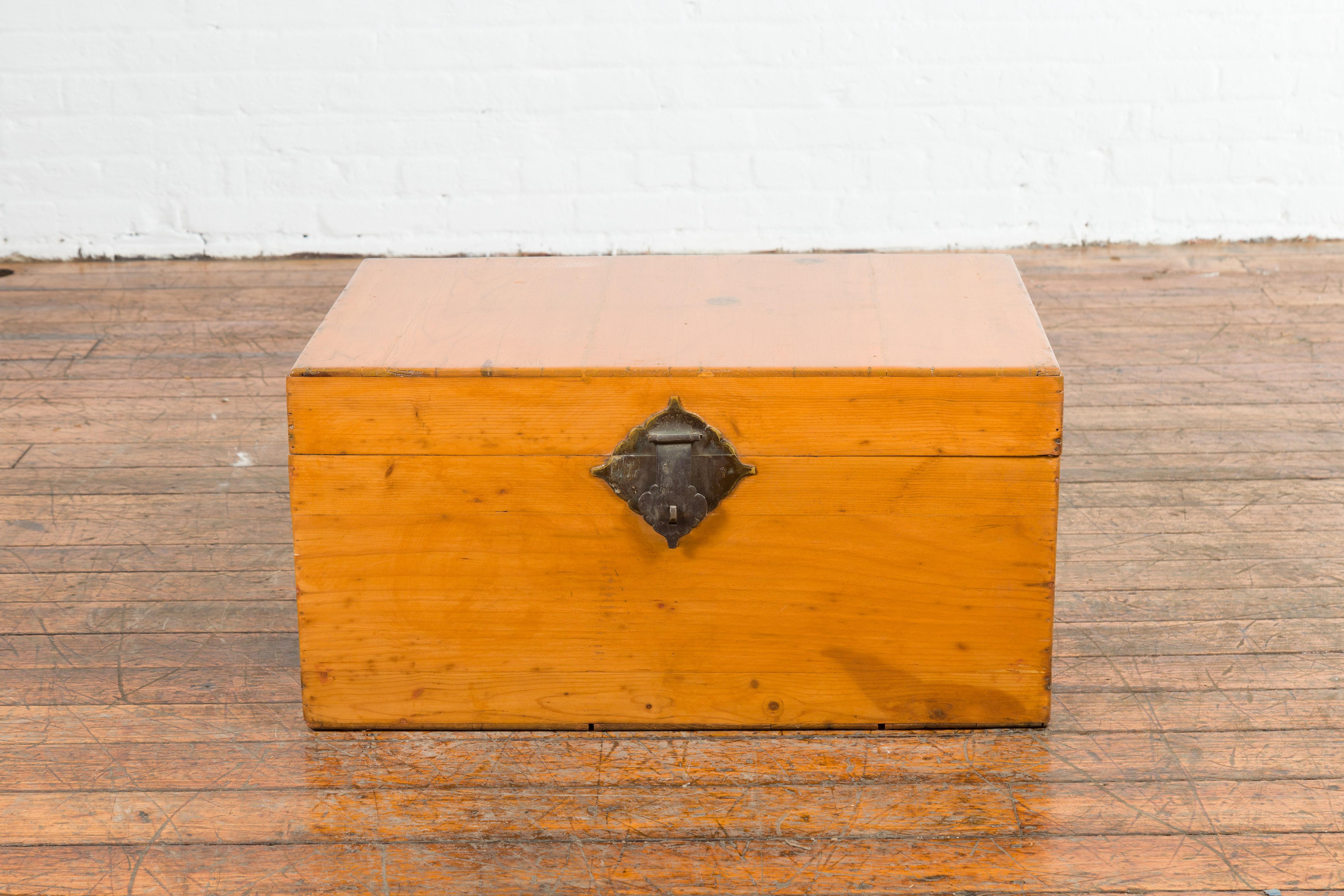 A Chinese elmwood blanket chest from the early 20th century, with brass hardware. Created in China during the early years of the 20th century, this elm blanket chest features a linear silhouette perfectly complimented by a warm honey hued patina.