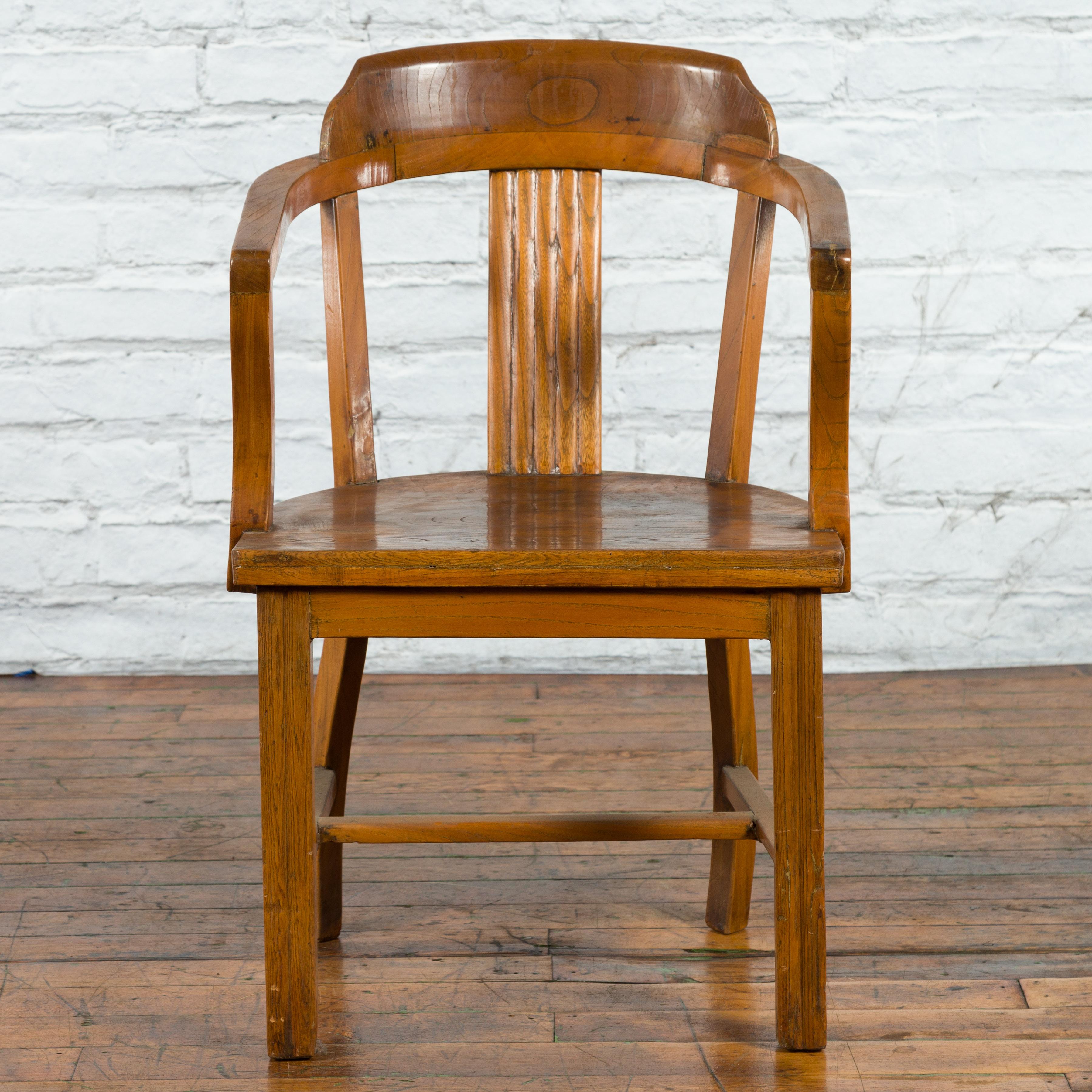 A Chinese wooden horseshoe armchair from the early 20th century with open back and arms, reeded splat and H-Form cross stretcher. Created in China during the early years of the 20th century, this wooden armchair features an open horseshoe back