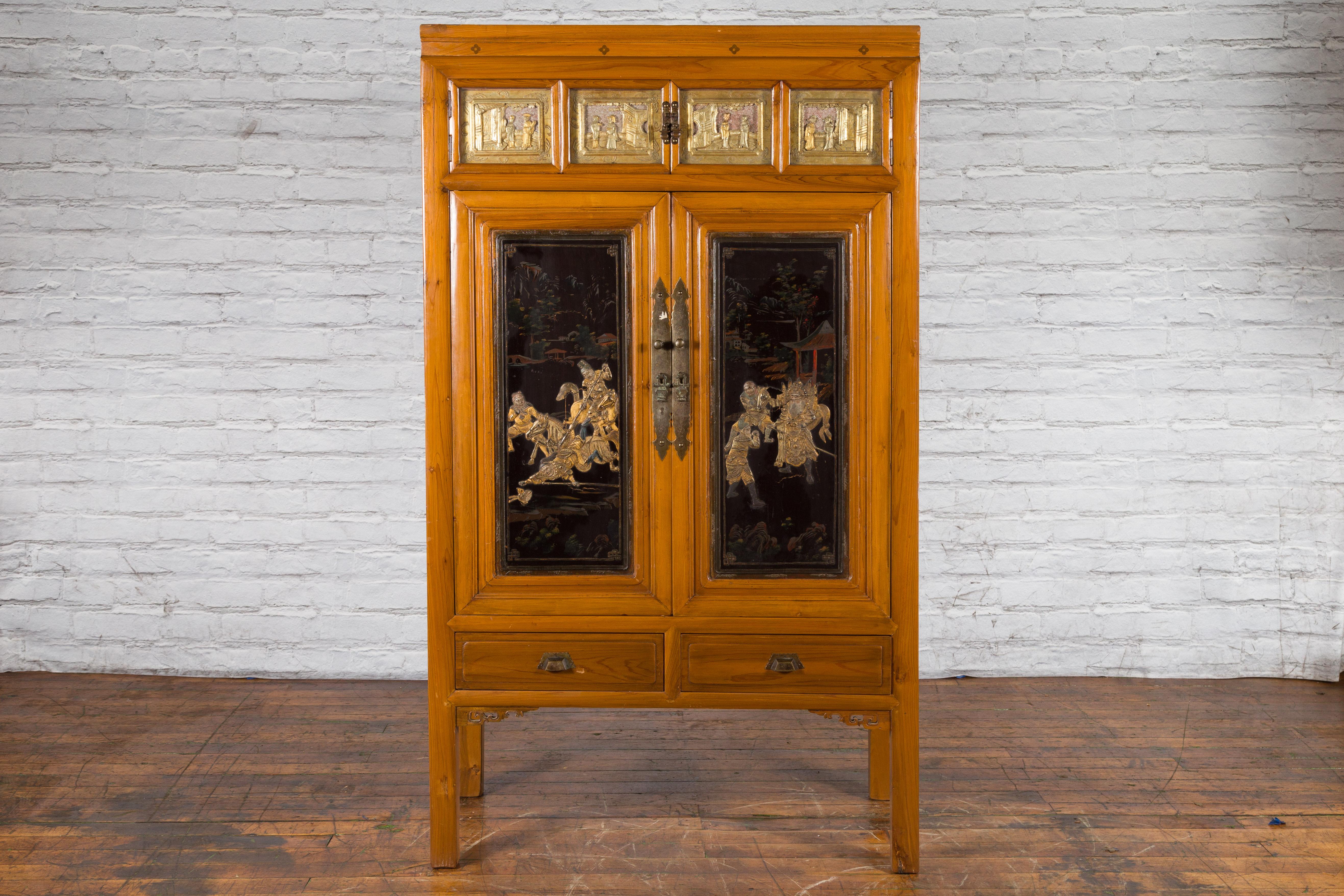 Early 20th century Chinese lacquered wood armoire with hand-carved gilt panels, doors and drawers. Created in the early years of the 20th century, this Chinese armoire features a linear silhouette accented by a natural wood patina. Two small doors