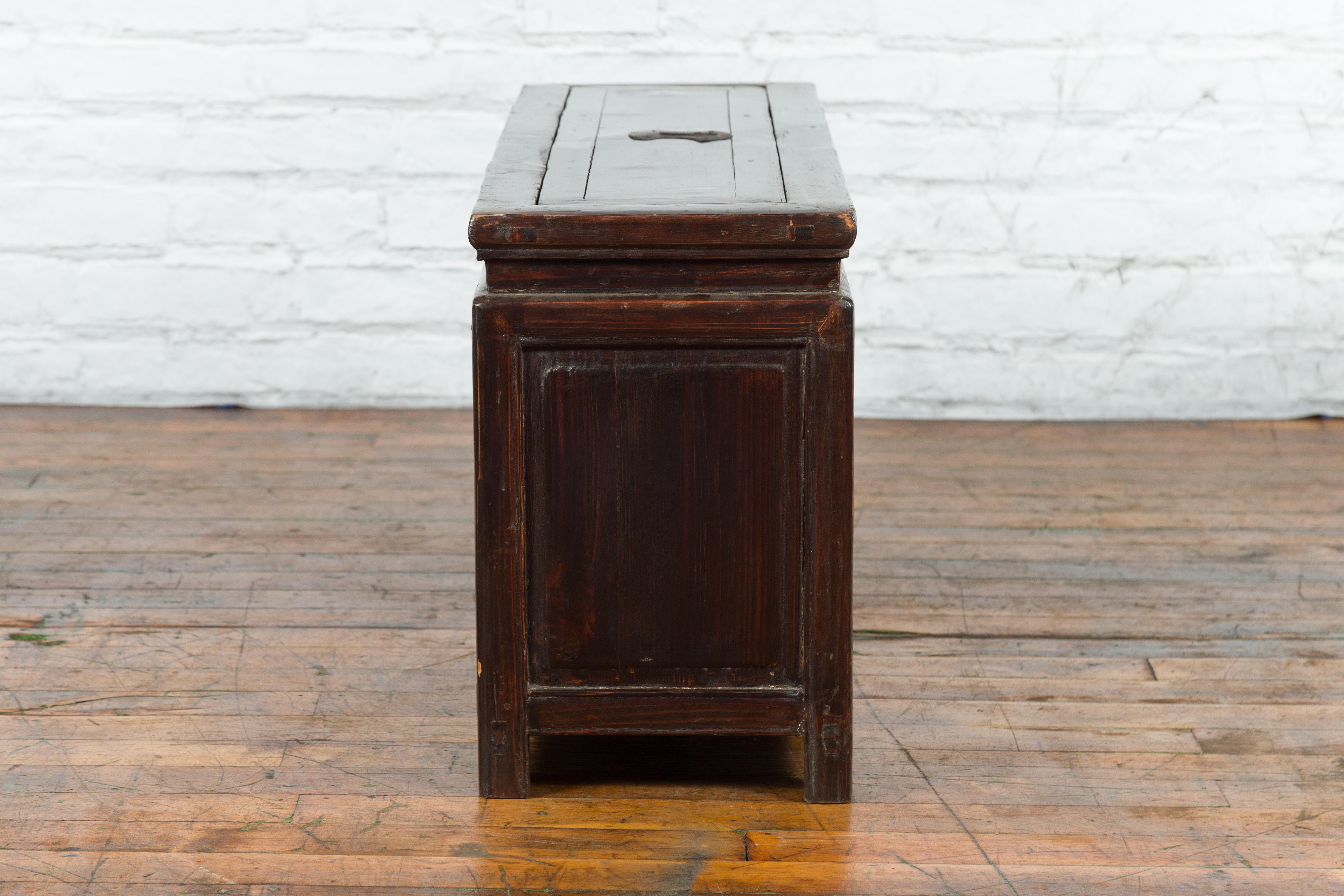 A Chinese lacquered wood trunk from the early 20th century, with brass hardware and removable top. Created in China during the early years of the 20th century, this trunk is covered with an elegant dark brown lacquer. Featuring a waisted top that