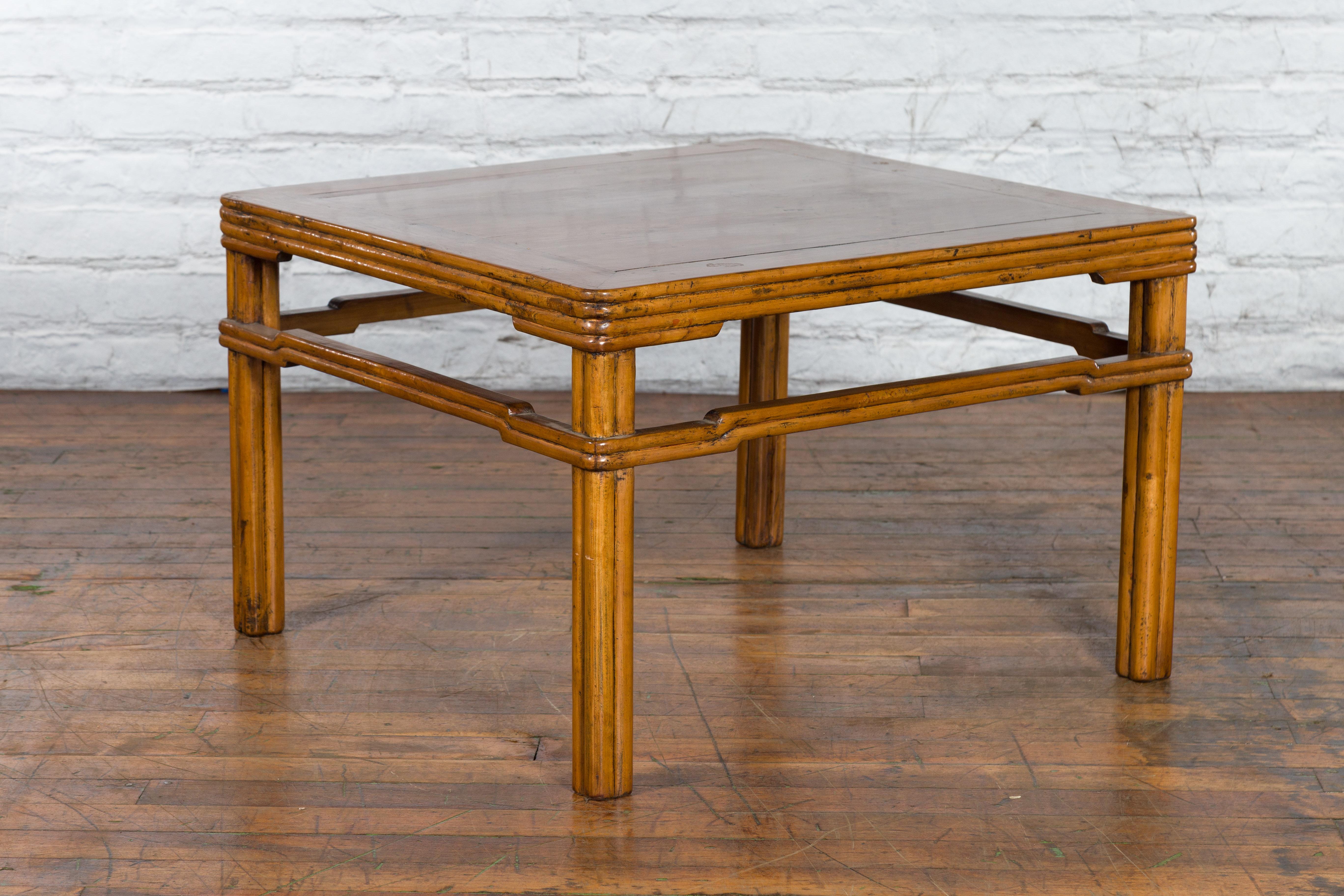 An antique Chinese low side table from the early 20th century, with reeded apron, humpback stretcher, straight legs and light brown lacquer. Created in China during the early years of the 20th century, this low side table features a square shaped