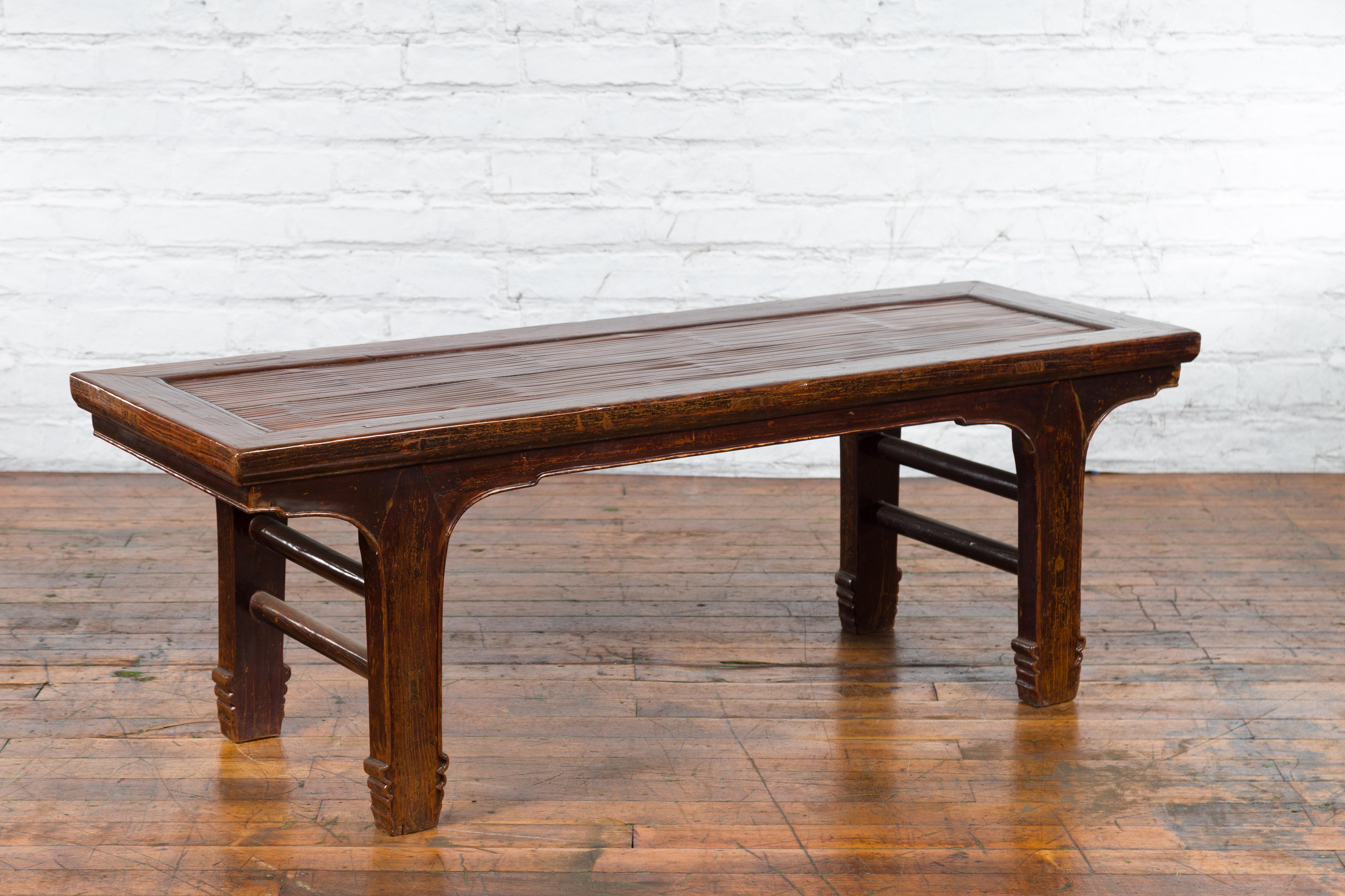 A Chinese low table from the early 20th century, with opium mat top and carved legs. Created in China during the early years of the 20th century, this low table could be used equally as a bench. The table features a rectangular bamboo opium mat top
