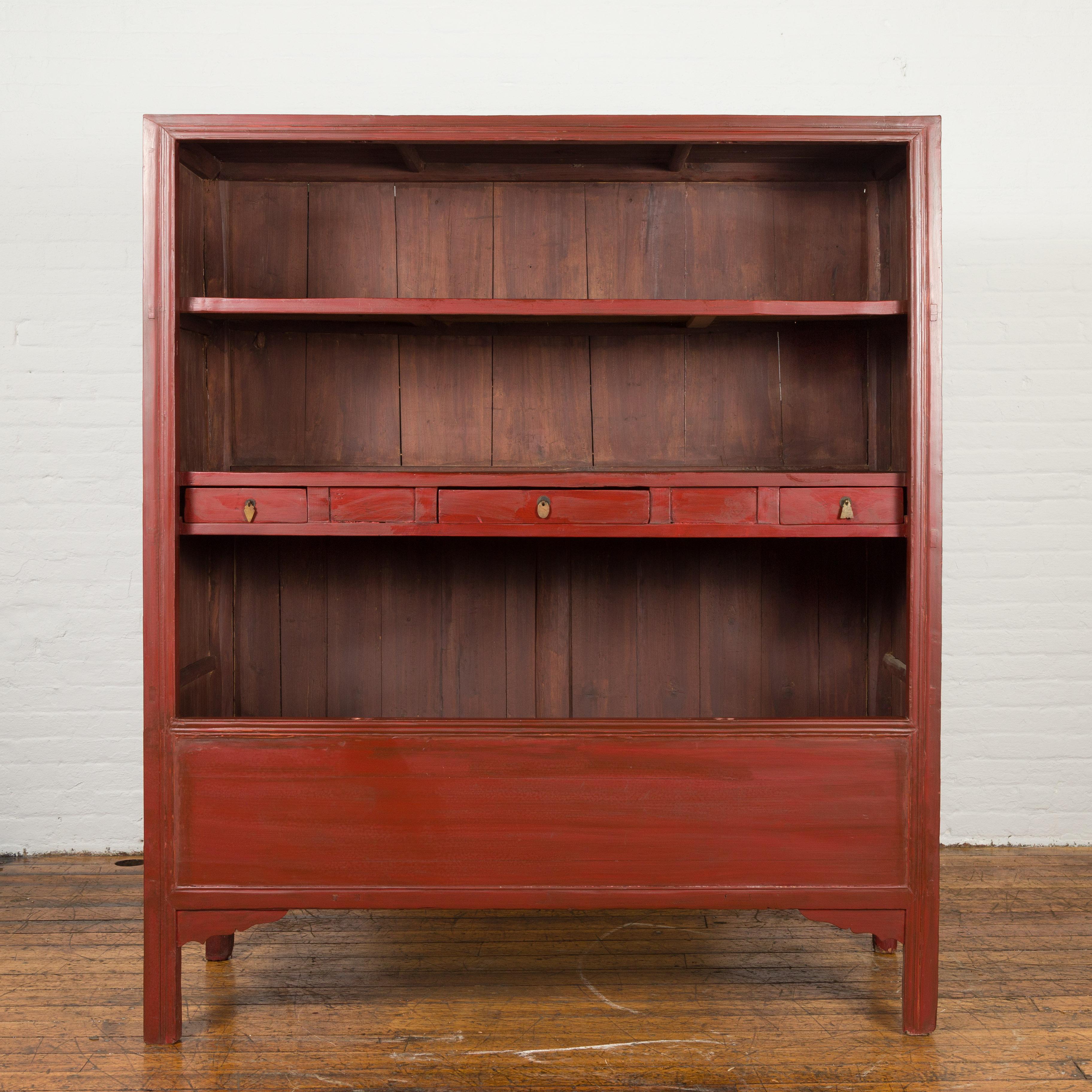 A Chinese antique cabinet from the early 20th century, converted into an open display cabinet with three drawers. Created in China during the early years of the 20th century, this red lacquered converted cabinet showcases a simple façade made of