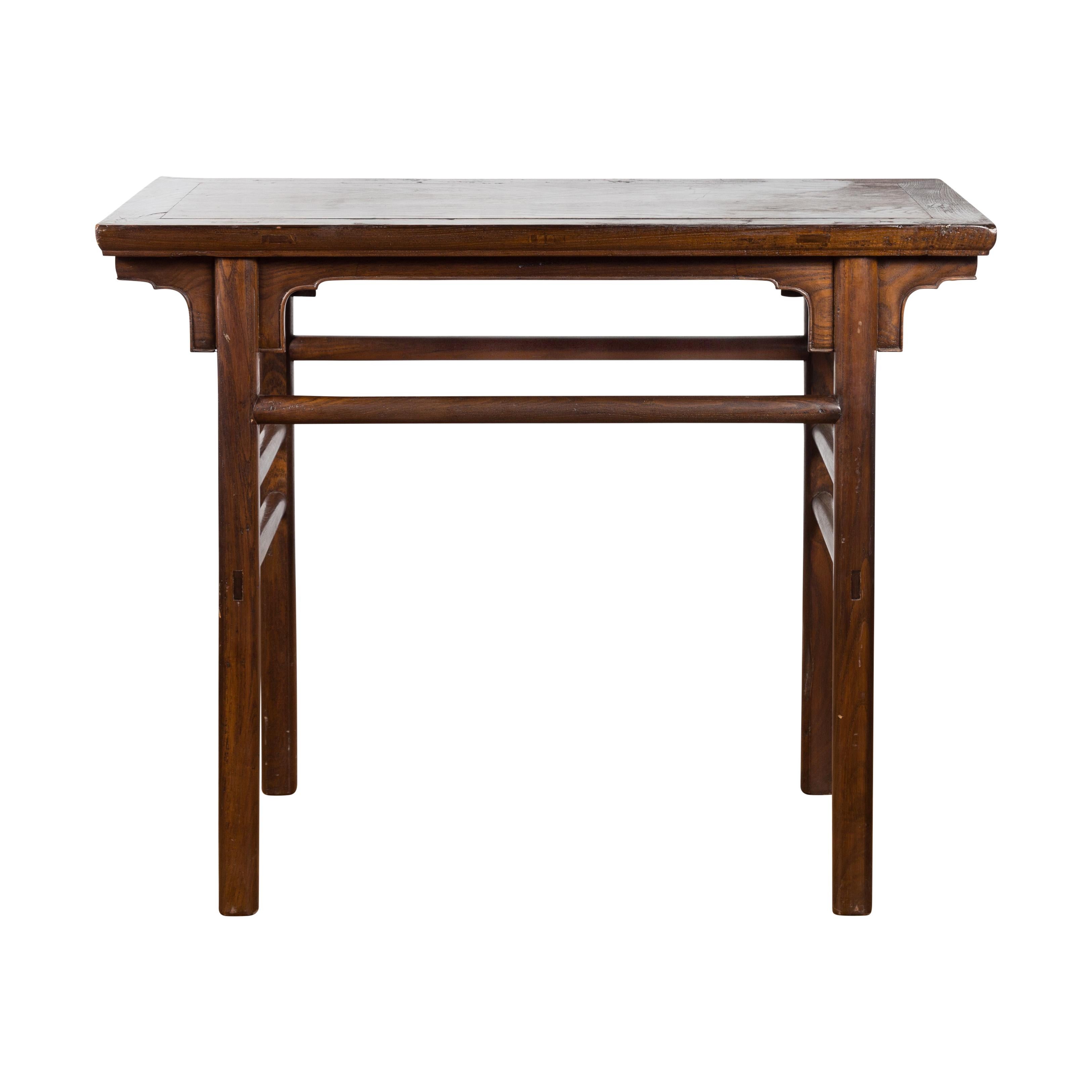 An antique Chinese scholar's altar table from the early 20th century, with carved apron and side stretchers. Created in China during the early years of the 20th century, this scholar's altar table features a rectangular top with central board,