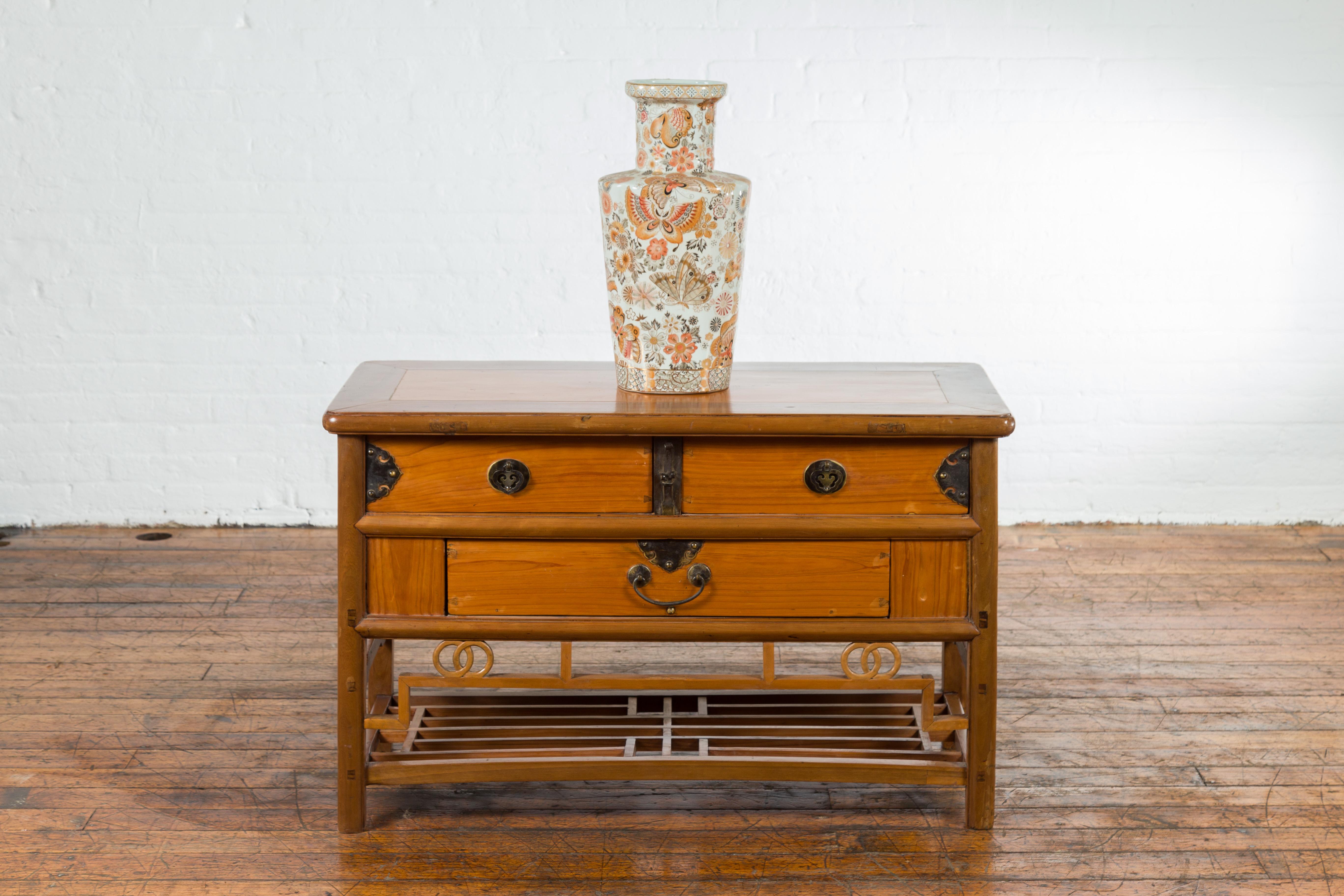 A Chinese sideboard from the early 20th century, with natural finish, three drawers and brass hardware. Created in China during the early years of the 20th century, this sideboard features a rectangular top with rounded edges, sitting above three