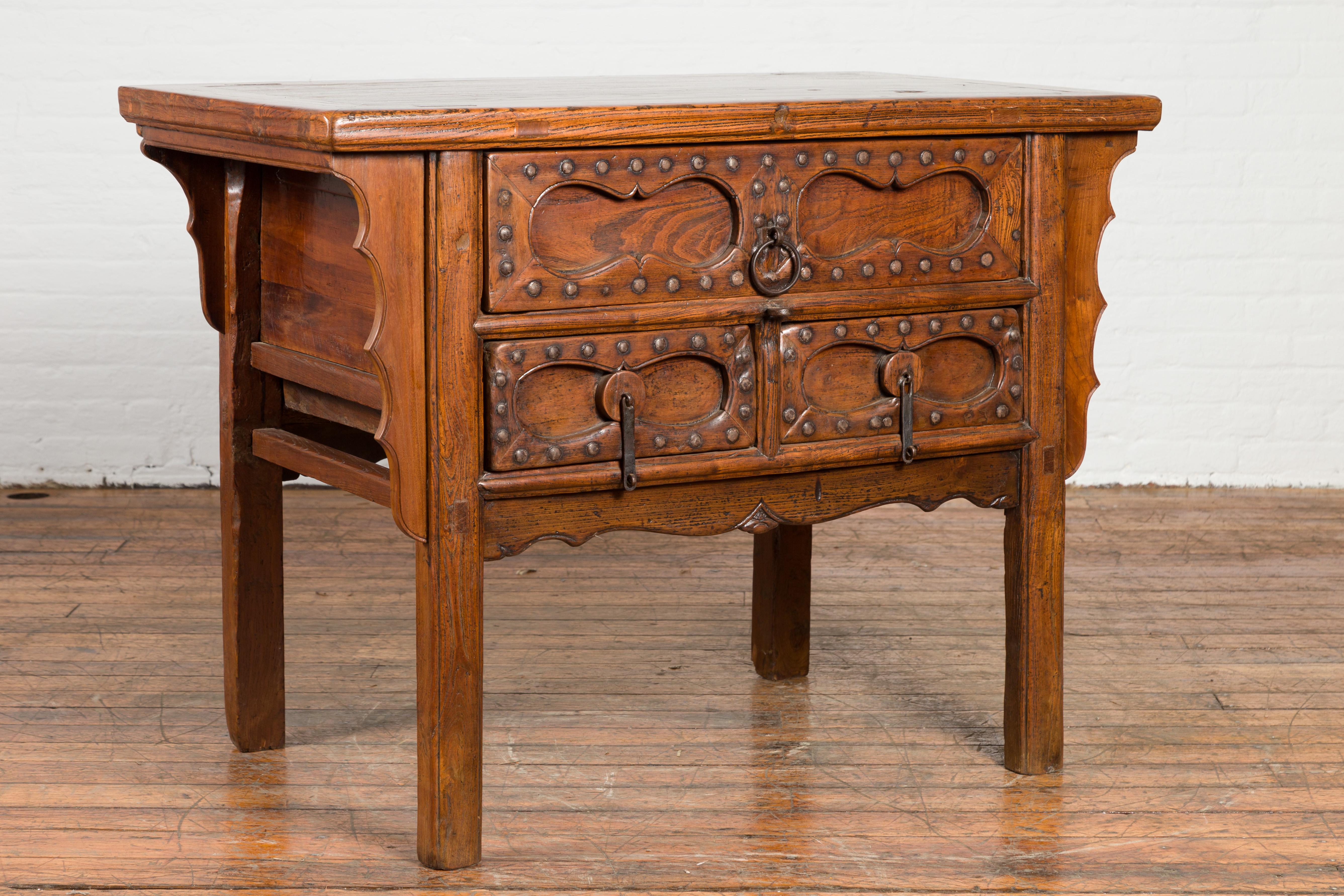 A Chinese antique coffer table from the early 20th century, with three drawers, studs and carved spandrels. Created in China during the early years of the 20th century, this antique coffer table features a rectangular top with central board, sitting