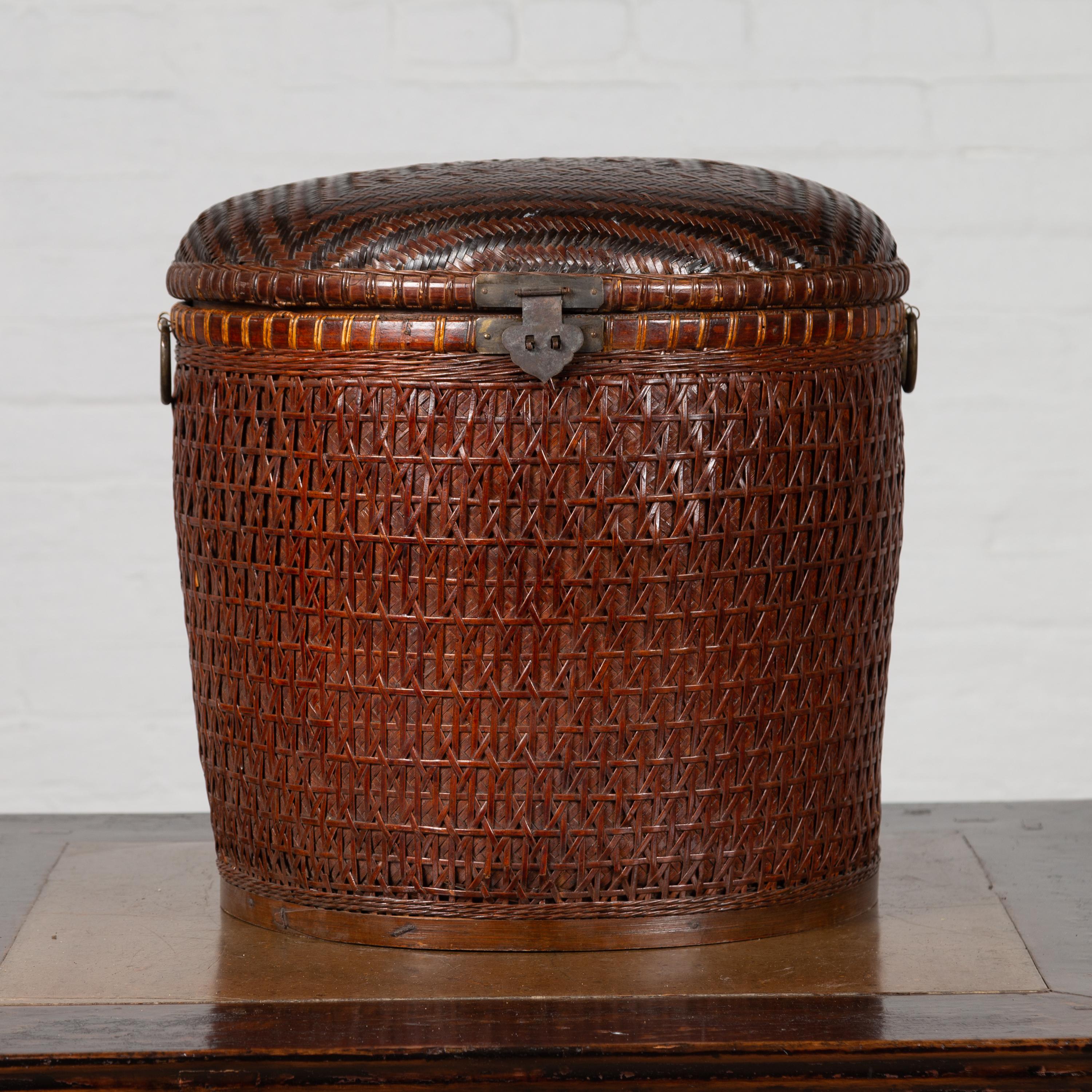 An antique one of a kind Chinese wood and rattan basket with lid from the early 20th century with black decorative patterns. Born in India, this charming basket features a brown rattan over wood structure, adorned with black decorative motifs on the