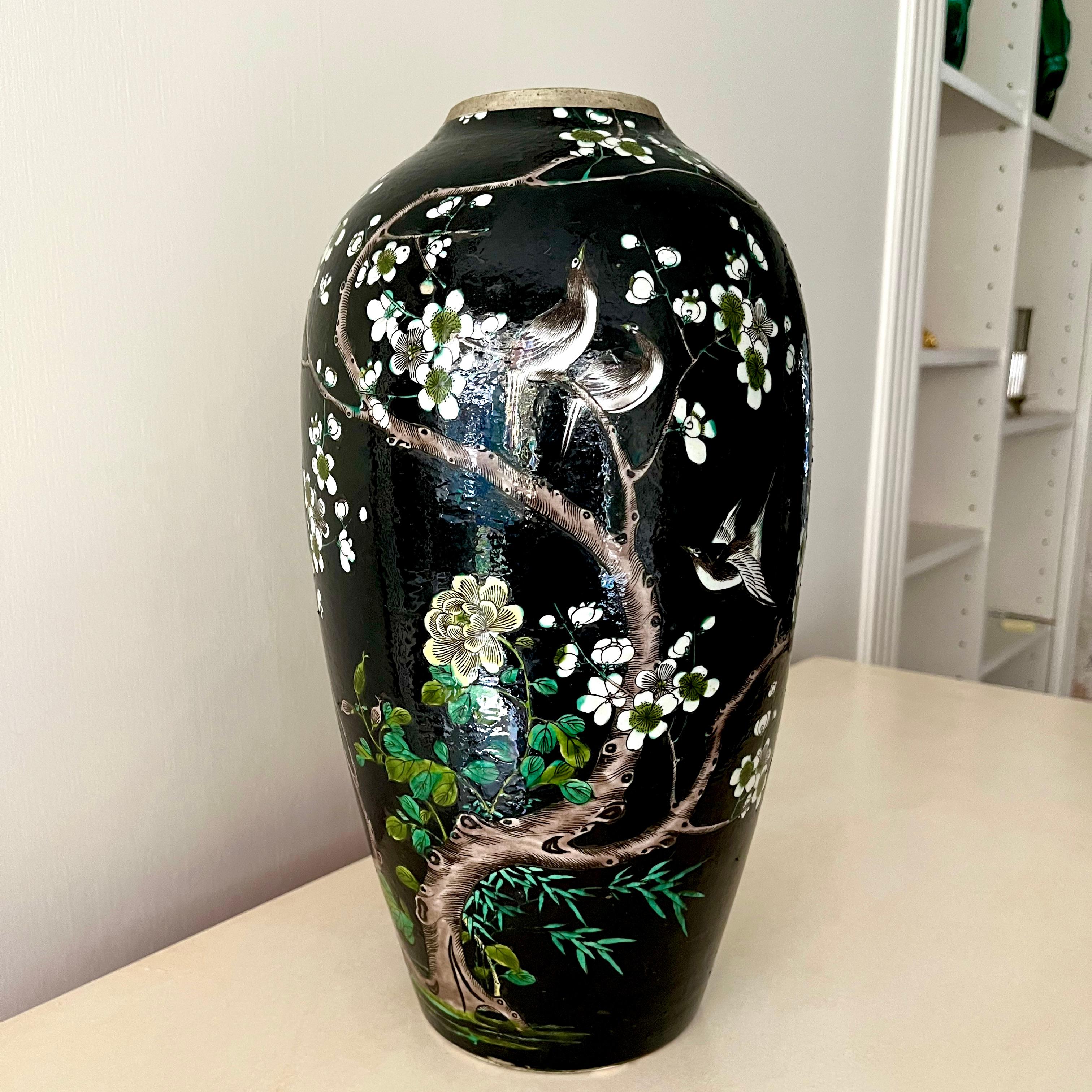 Vaso cinese di inizio Novecento smaltato di nero e decorato con uccelli e farfalle intorno a un albero di peonie in fiore. 
Piccola scheggiatura sotto il tallone del vaso