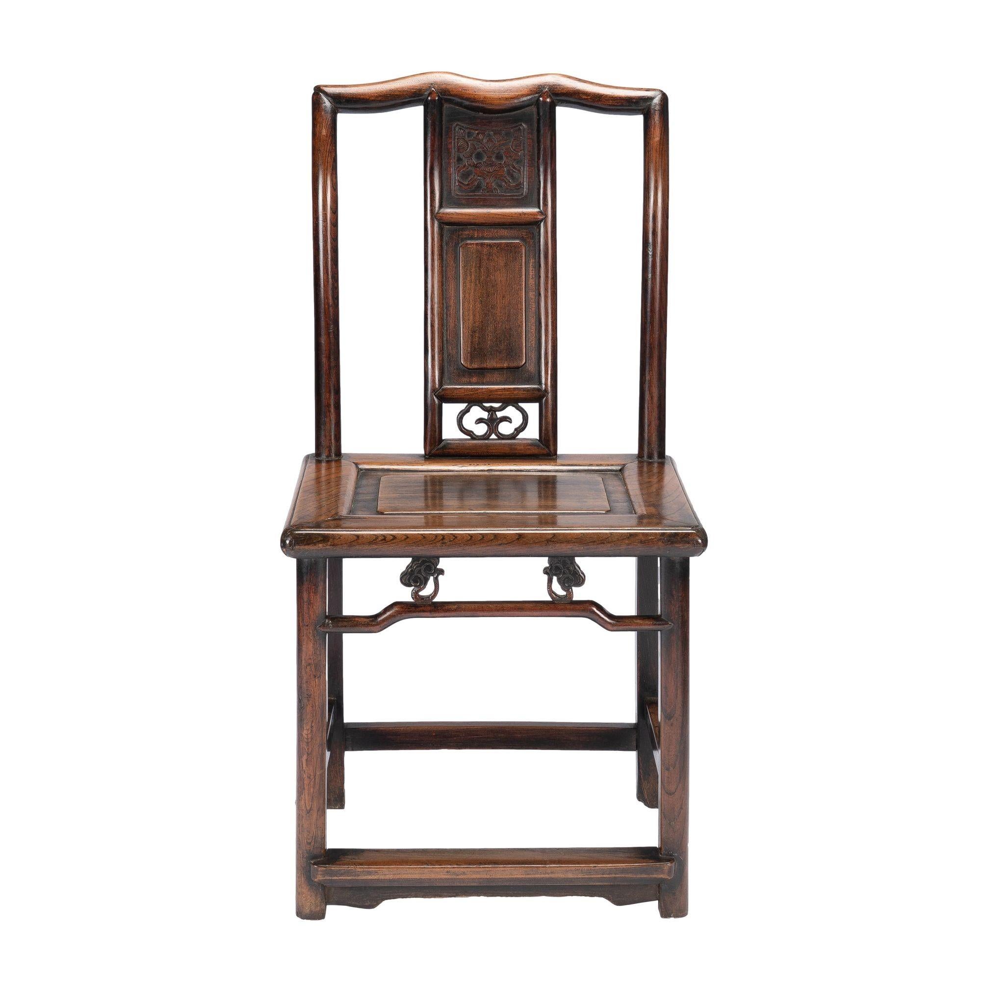 Chinese audience chair in the Ming Dynasty taste. The chair is made from Northern Chinese Elm with traces of original black lacquer throughout. The chair has a frame and panel seat with turned back rails which resolve into a splayed and yoke carved