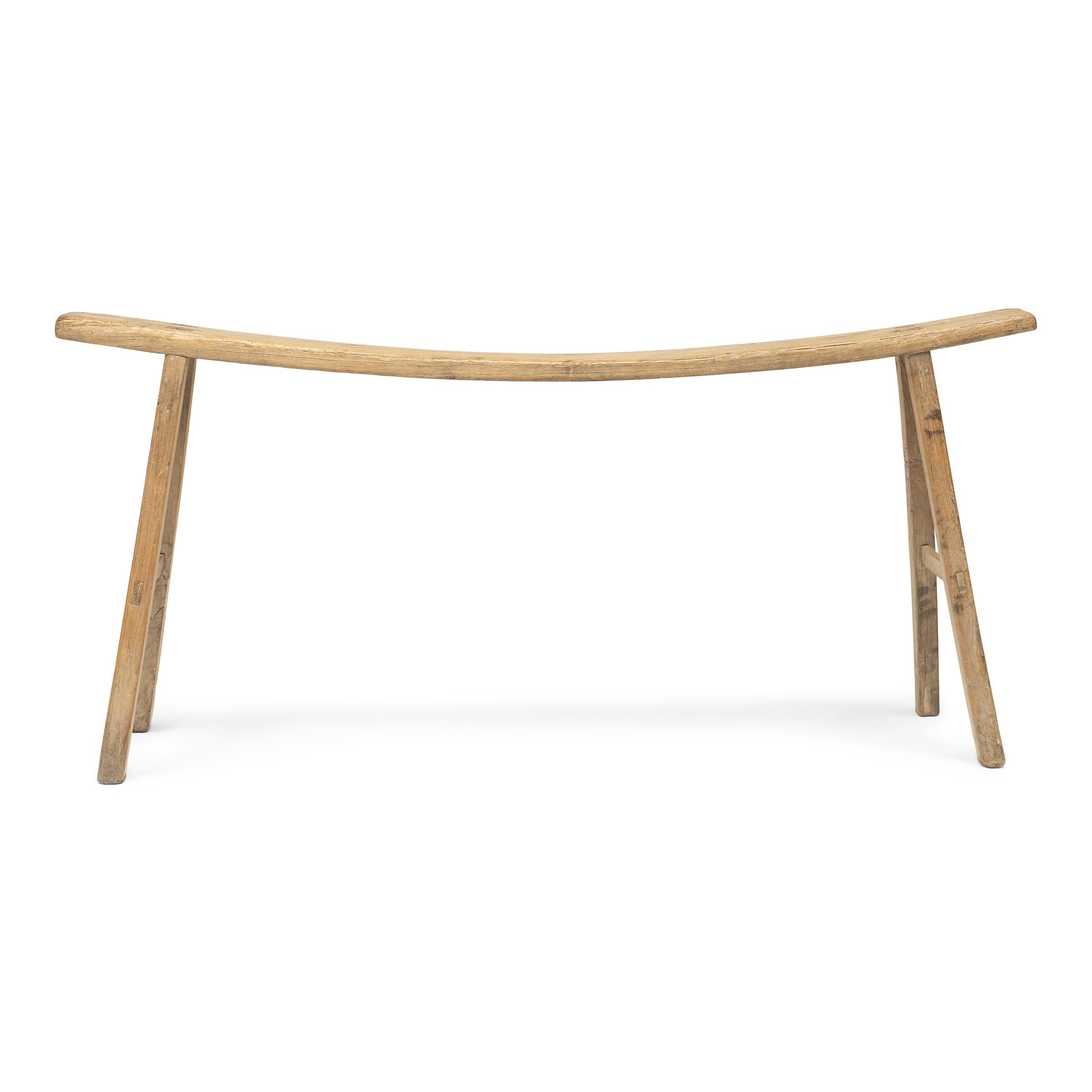 Bending like the swaying bough of an elm tree, this early 20th-century courtyard bench from China's Shanxi province captivates with a delicate silhouette and graceful asymmetry. Shaped from a young elmwood branch, the narrow seat follows the natural
