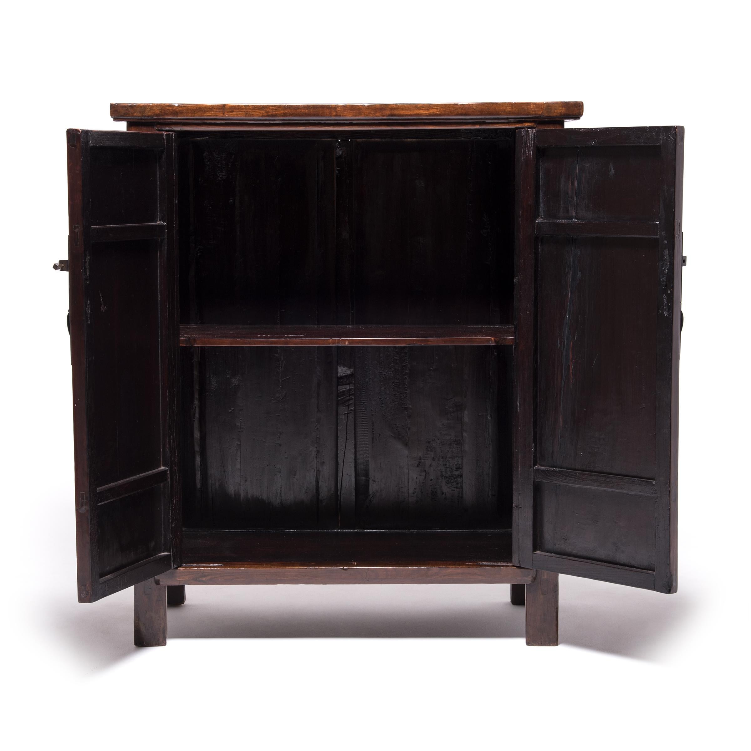 Classic Chinese furniture design is characterized by the flawless construction, purity of line, and dedication to detail you see here in this two-door cabinet. This beautiful elmwood cabinet was created in the mid-19th century by an artisan from