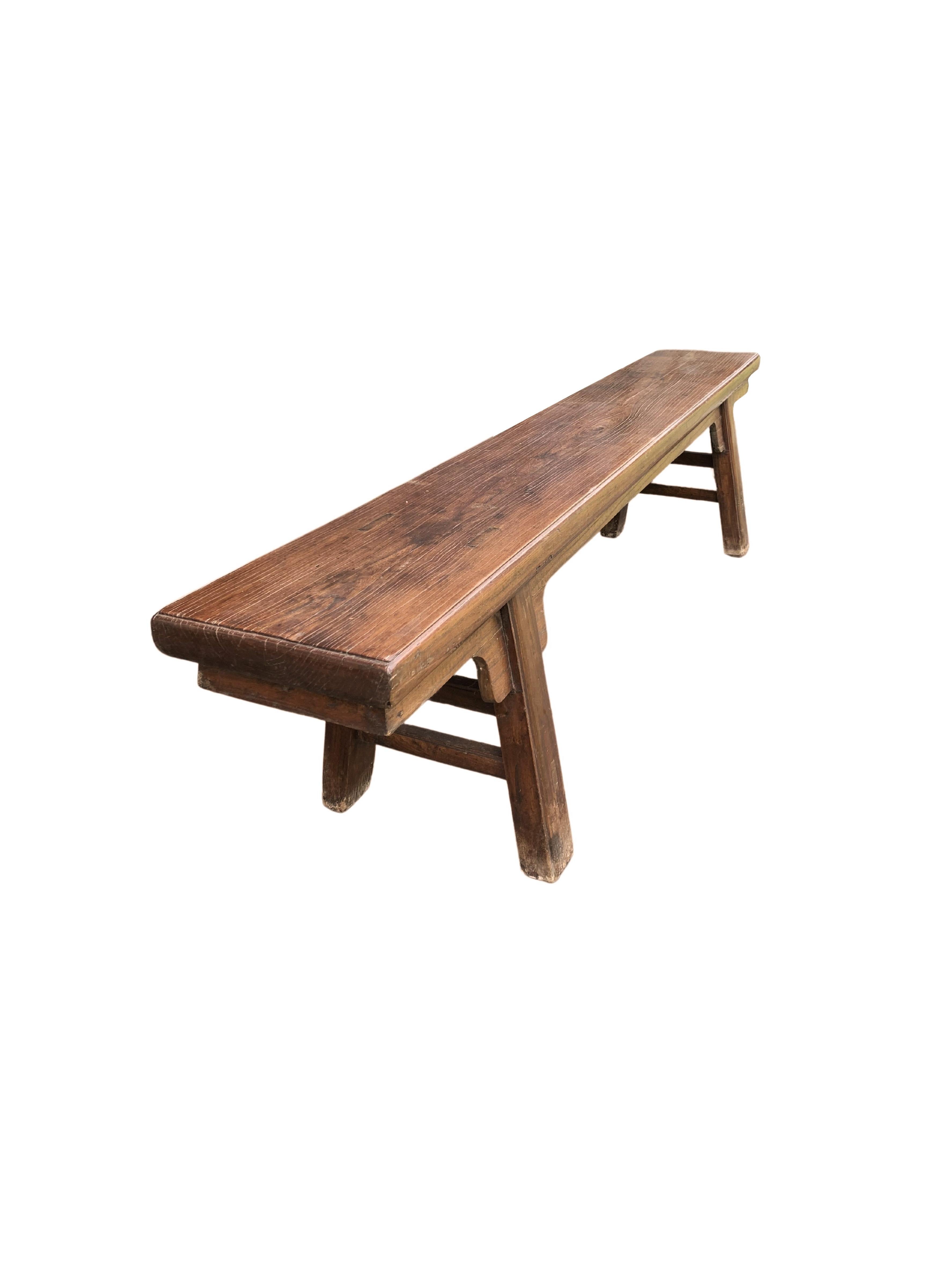 This Chinese long bench from the Qing Dynasty was crafted from elmwood & features straight legs with double stretchers and a solid top. It features a more than centuries old lacquer finish and age related patina and textures. A true testament to