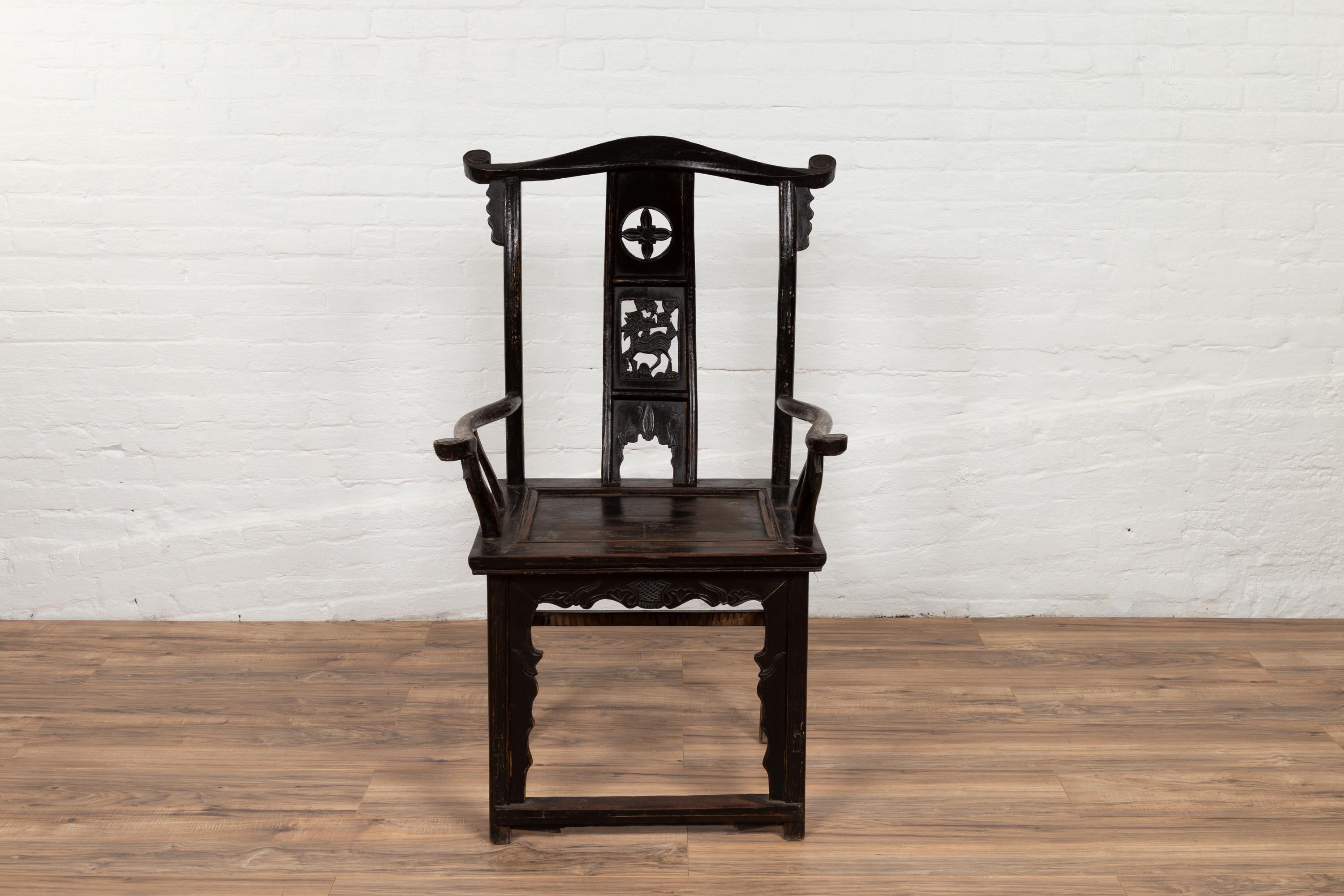 A Chinese elmwood scholar's lamp-hanger armchair from the late 19th century, with carved splat, dark patina, curving arms and side stretchers. Born in China in the later years of the 19th century, this scholar's lamp-hanger chair called dengguayi